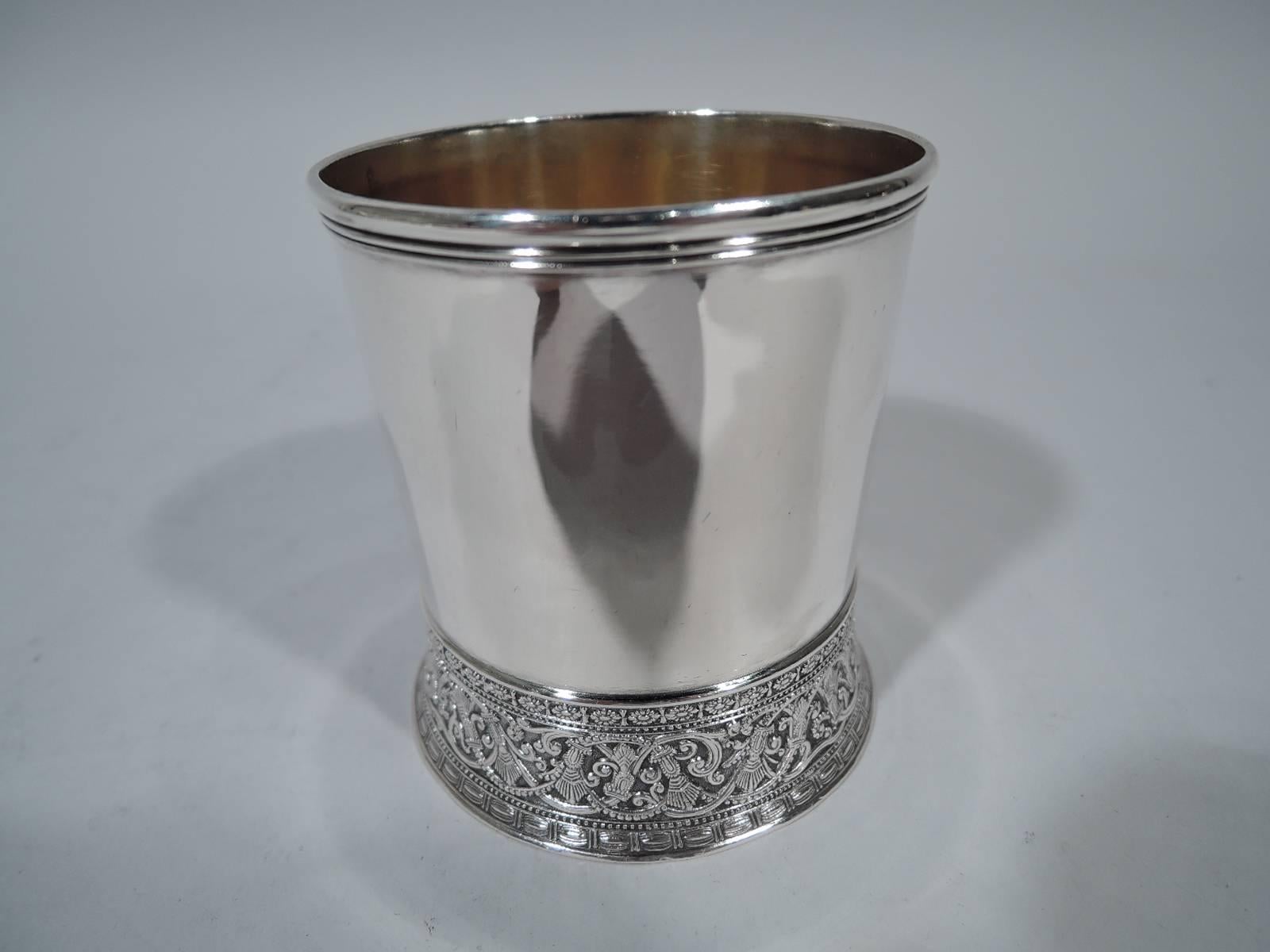 Aesthetic sterling silver baby cup. Made by Gorham in Providence in 1883. Straight and plain. Base spread and ornamented with stylized rinceaux, beading, and rosettes. Bracket handle with leaf under cap. Gilt interior. Hallmark includes date letter