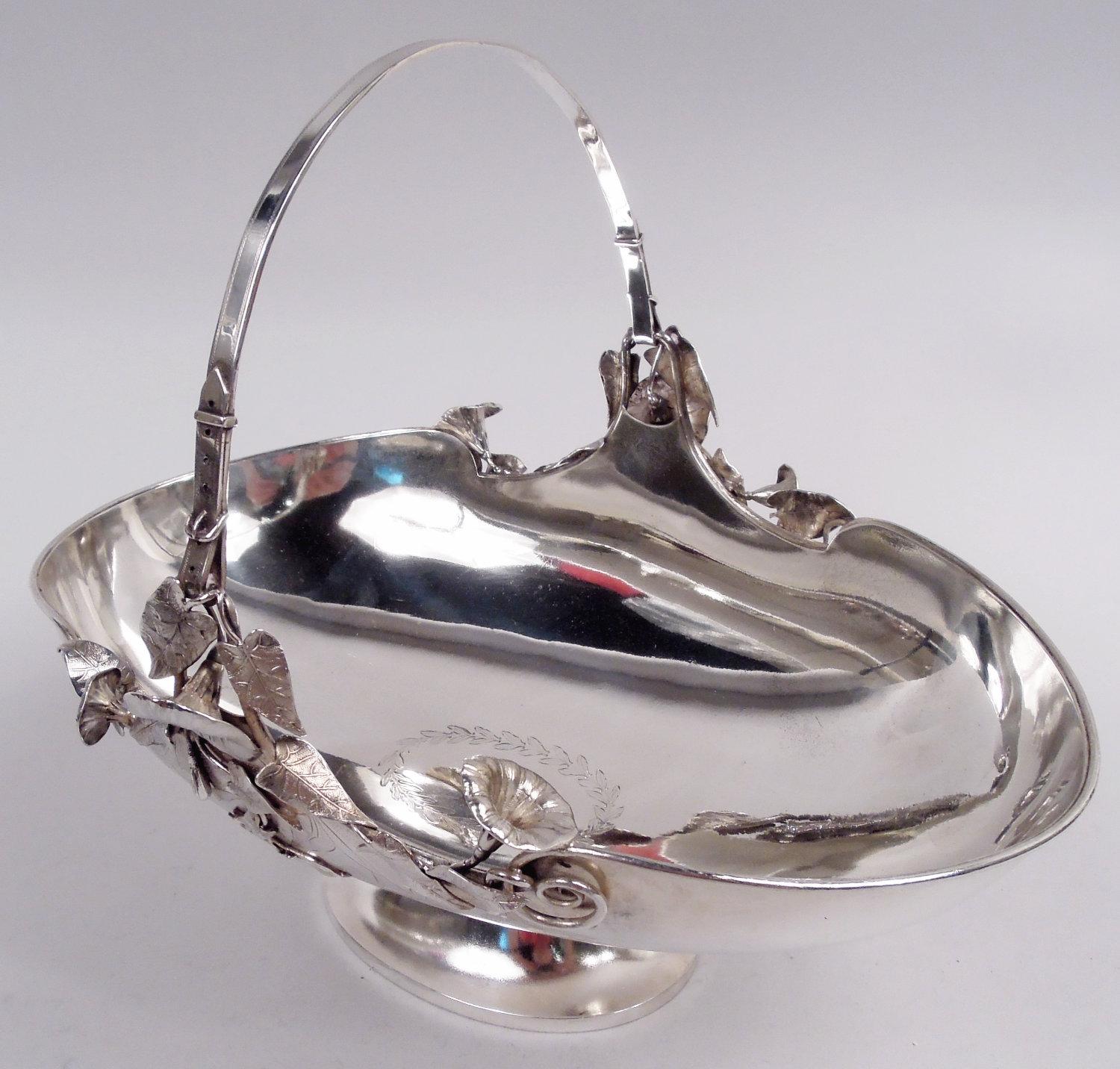 Esthétique panier en argent sterling. Fabriqué par Gorham à Providence en 1874. Coupe ovale sur pied bombé. L'anse est attachée à des boucles enfilées avec des lys calla qui s'enroulent autour du bord du panier et chevauchent des branches feuillues