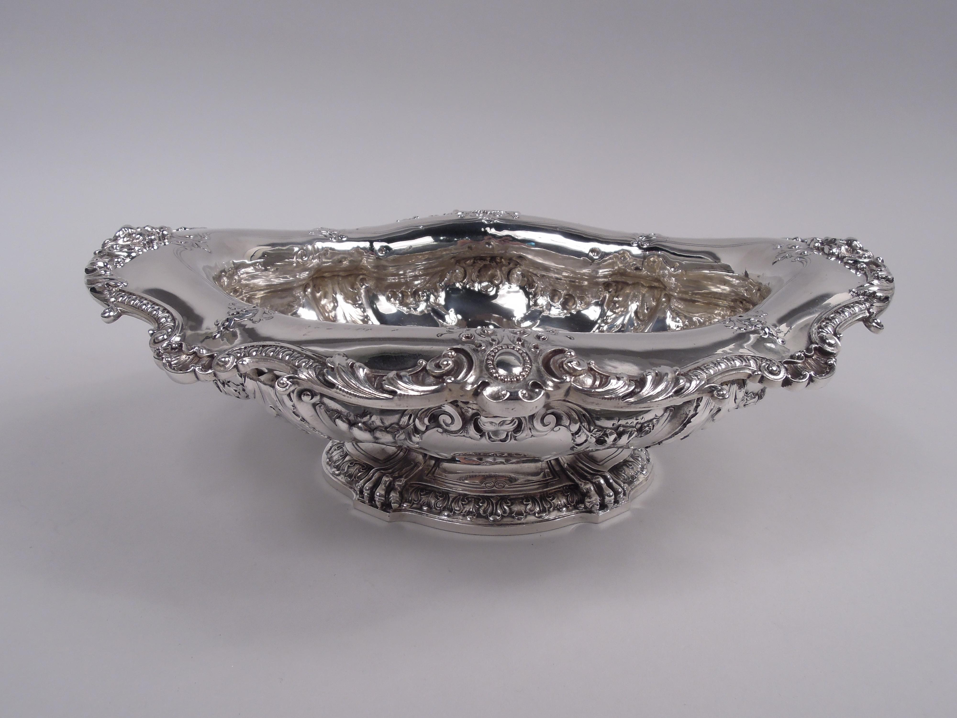 Cuenco eduardiano clásico de plata de ley. Fabricado por Gorham en Providence en 1900. Panzuda y ovoide sobre pie elevado. Borde ovoide envuelto en hojas, intercalado con hojas y óvalos de cuentas (vacíos); cabezas de león en los extremos. En los