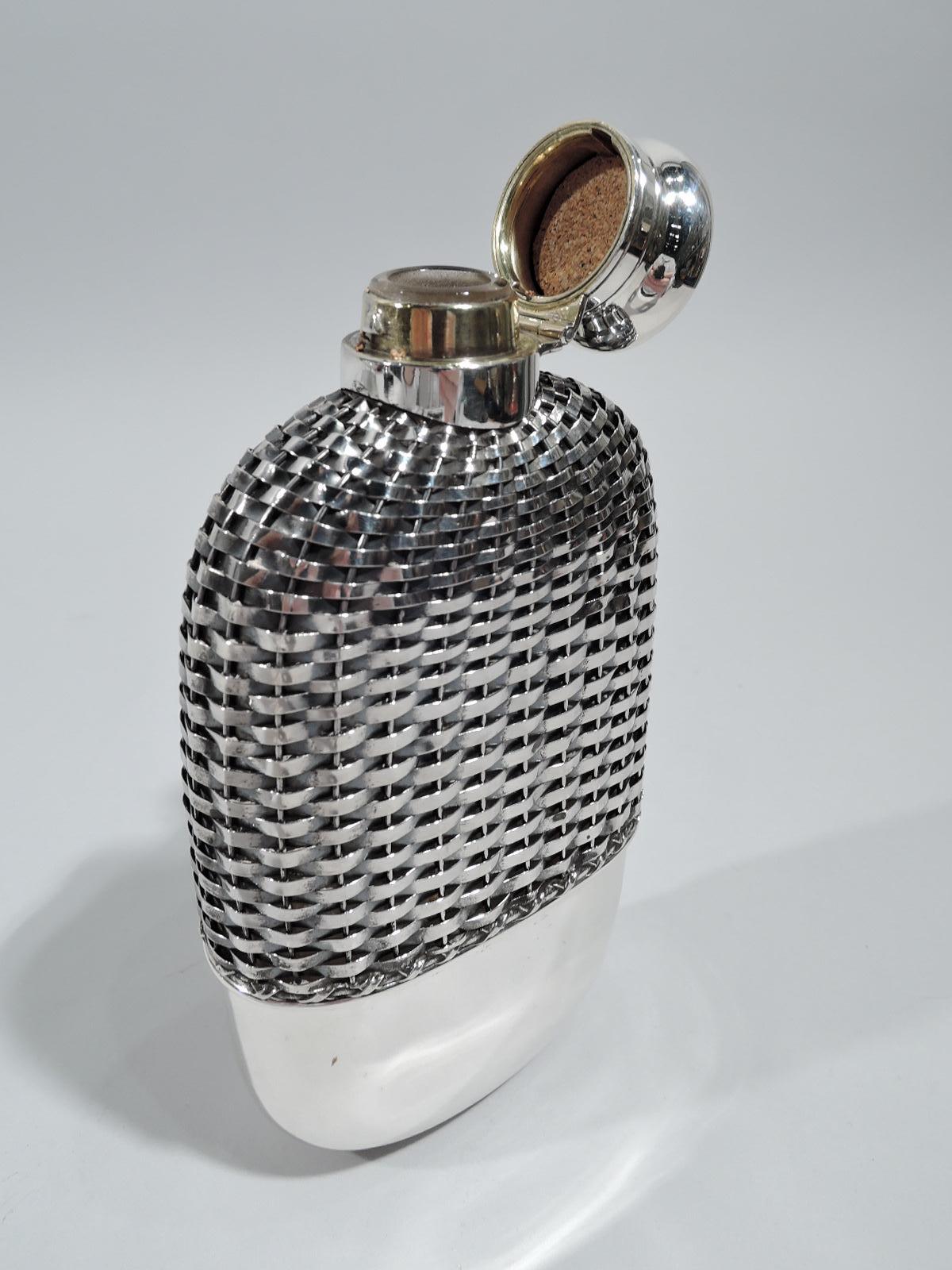 Edwardian flask. Made by Gorham in Providence, ca 1910. Clear glass body with detachable sterling silver cup at bottom. Top covered in sterling silver weave. Short neck in sterling silver collar with hinged and cork-lined bayonet cover. Perfect for