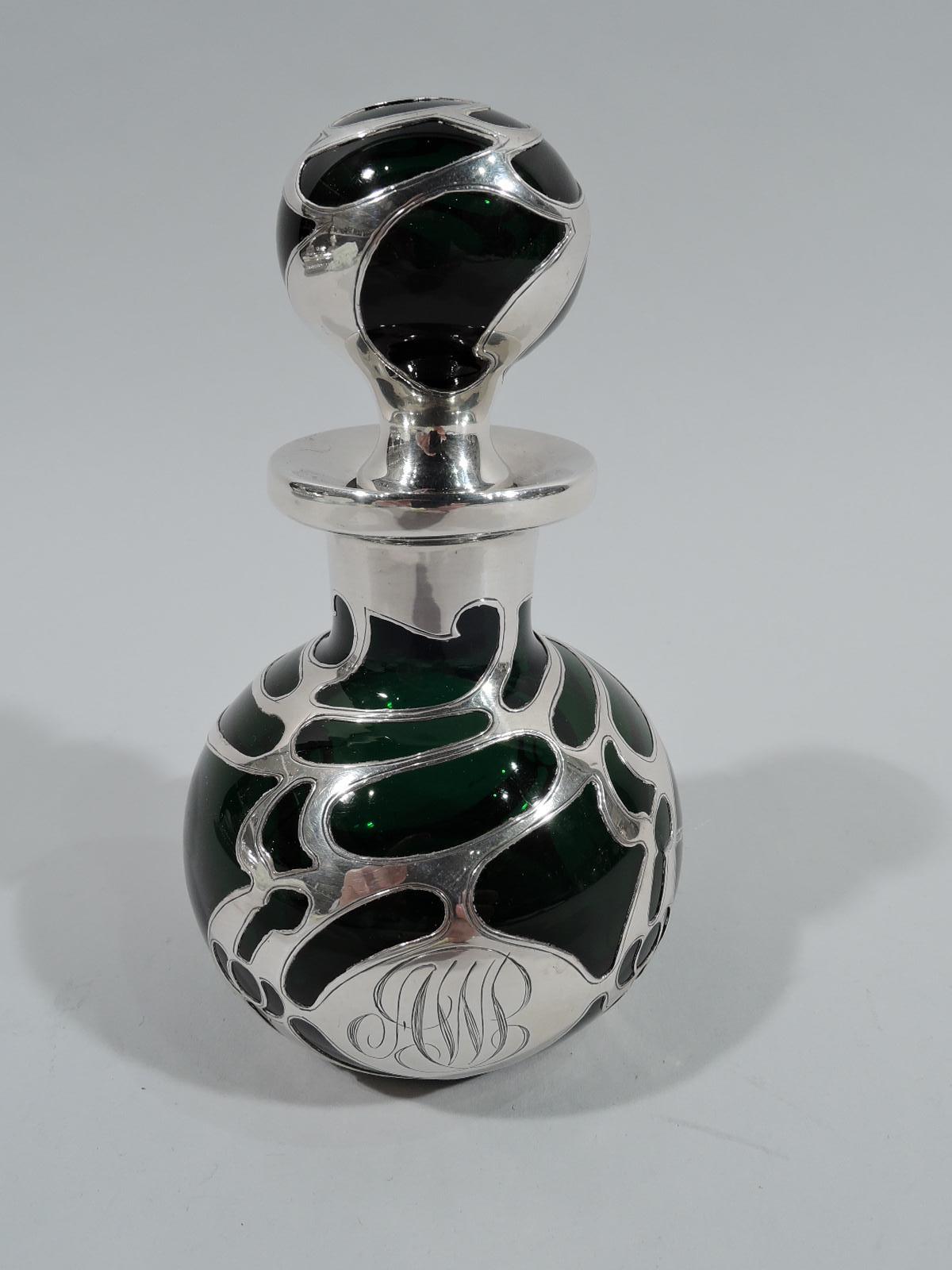 Turn-of-the-century Art Nouveau perfume with silver overlay. Globular bottle with short straight neck and everted rim in silver collar. Ball stopper. Overlay in biomorphic form with open irregular shapes. Engraved interlaced script monogram. Glass