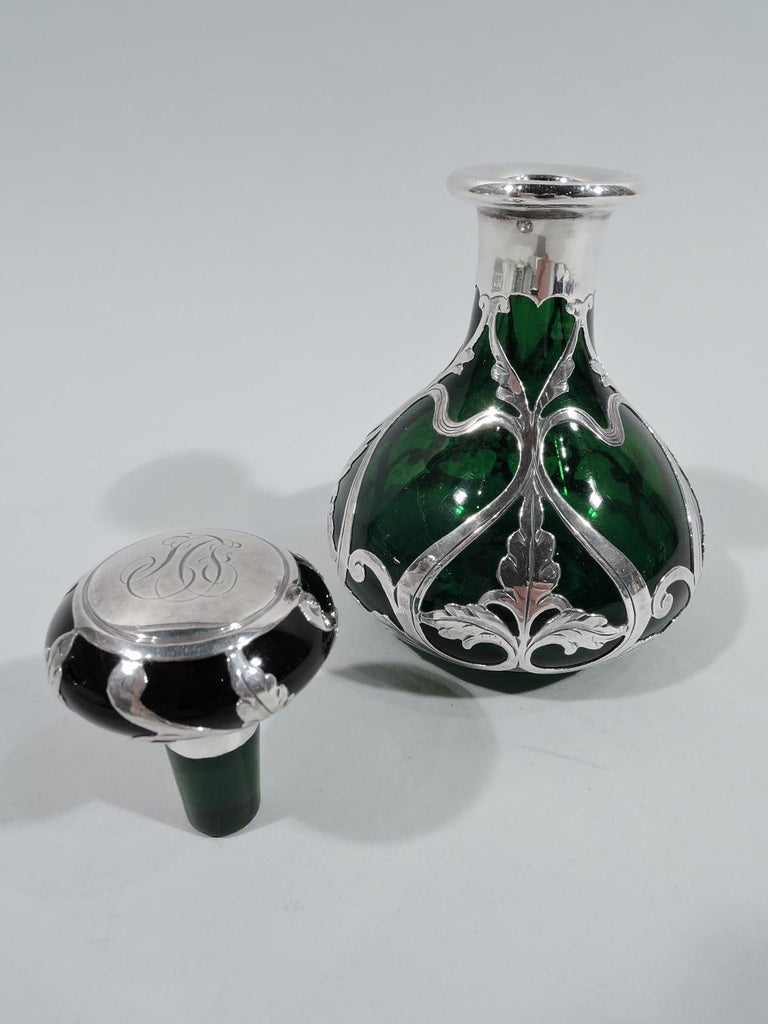 Turn-of-the-century Art Nouveau glass perfume with engraved silver overlay. Made by Gorham in Providence. Curved conical body with short upward tapering neck and everted rim in silver collar. Flat and round stopper. Overlay pattern comprising fluid
