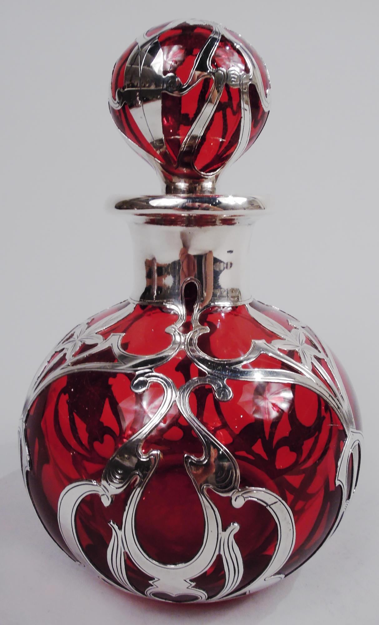 Profumo in vetro in stile Art Nouveau con sovrimpressione in argento inciso. Prodotto da Gorham a Providence, nel 1900 circa. Globulare con collo corto e bordo estroflesso in colletto d'argento; tappo a sfera. Sovrapposizione a forma di intreccio e