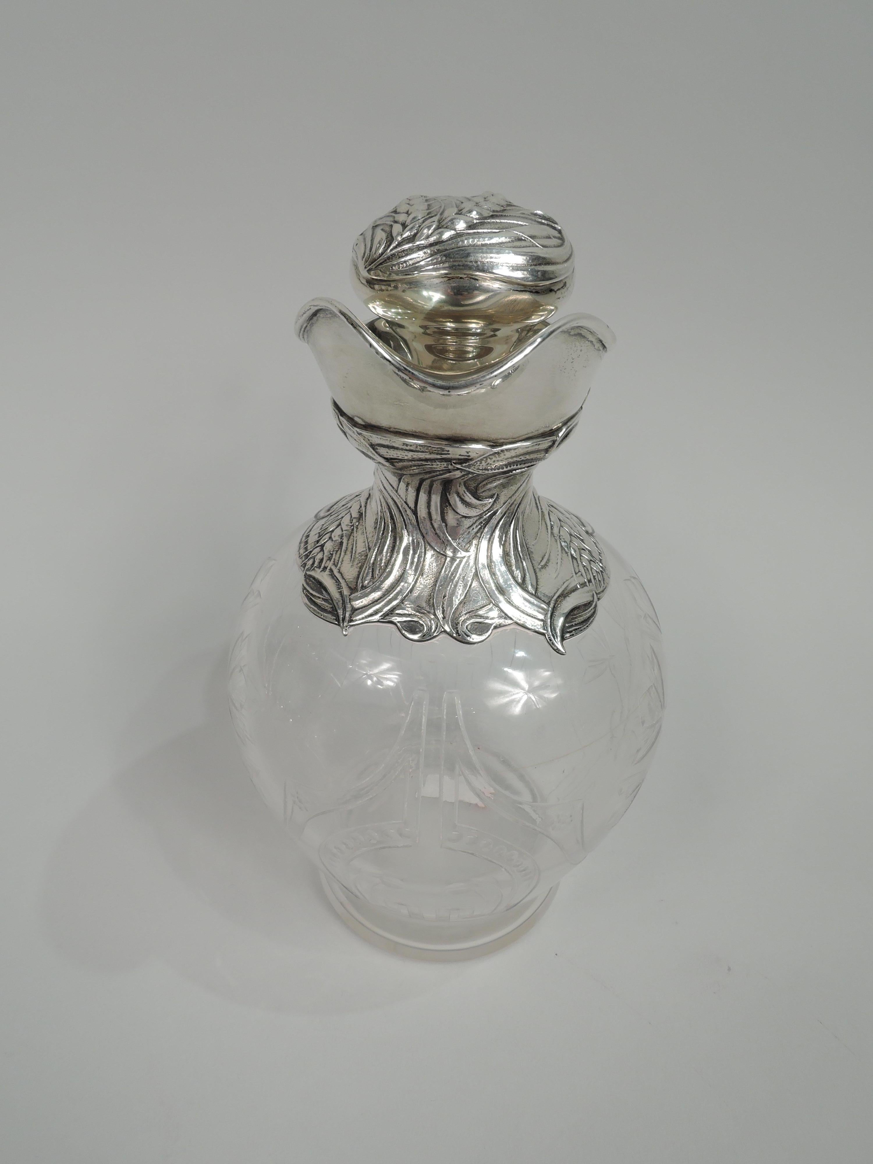 Turn-of-the-century Art Nouveau sterling silver and crystal decanter. Made by Gorham in Providence. Ovoid crystal bowl with cut and engraved ornament: Beaded horse shoe in curvilinear strapwork frame, and stylized thistles. Sterling silver helmet