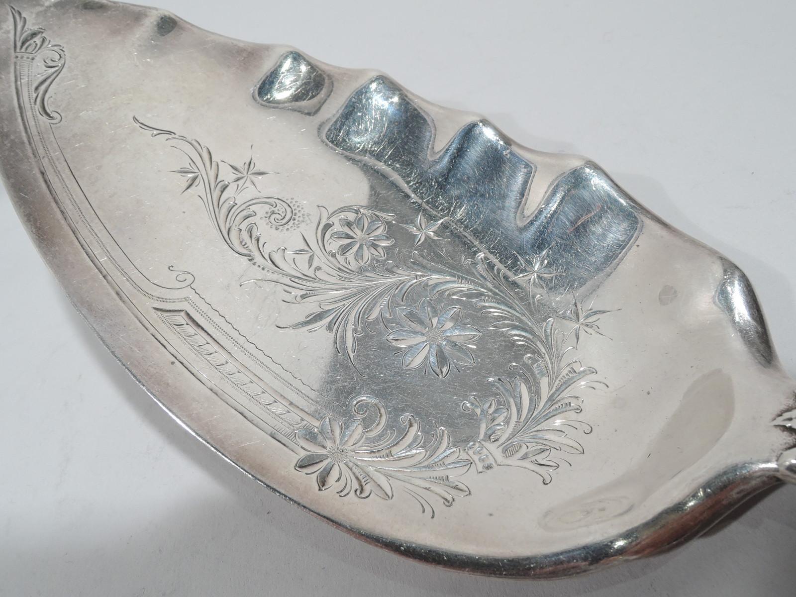 Cluny sterling silver fish server. Made by Gorham in Providence. Ovalish and crimped blade with engraved and brite-cut leaf and flower ornament. Handle tapering with dense flower heads as well as patera, beading, and volute scrolls in low relief. A