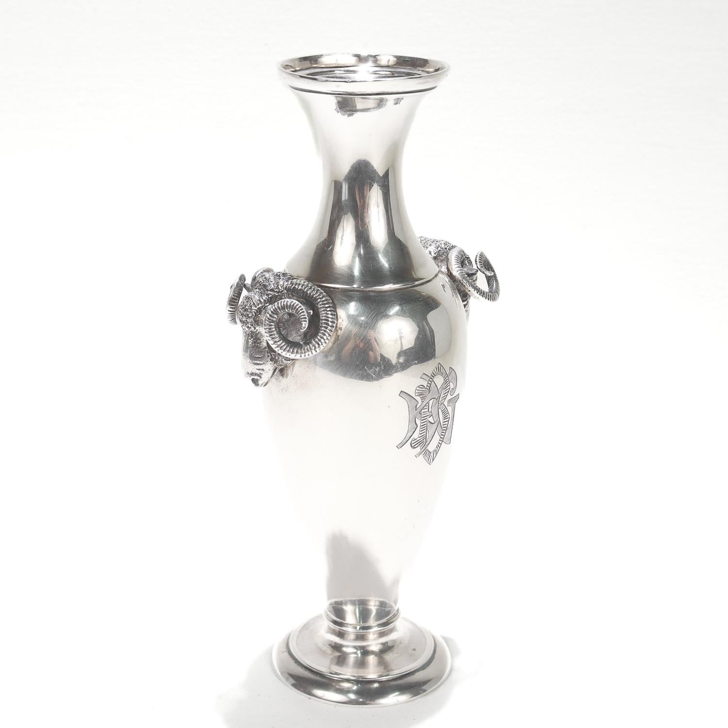 Un bel vaso antico in argento con moneta americana.

Da Gorham.

In stile revival greco con due manici figurati a testa di ariete ai lati opposti di un corpo a forma di anfora sostenuto da un piede svasato.

Alla base è presente il marchio del