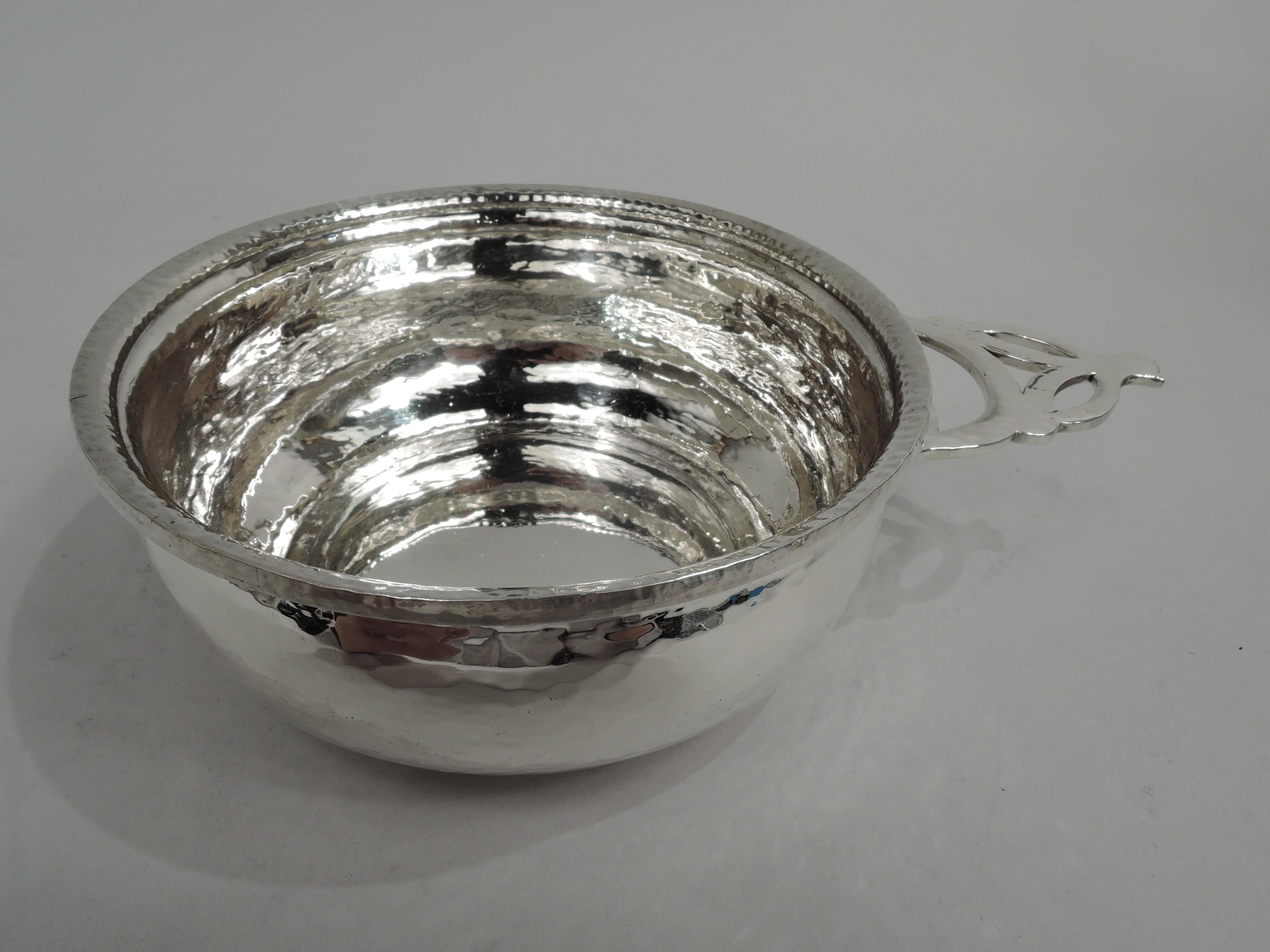 Craftsman sterling silver porringer. Made by Gorham in Providence, ca 1910. Traditional form. Unusual open geometric handle. Allover spot hammering. Fully marked including maker’s stamp and no. A5235. Weight: 7.8 troy ounces.