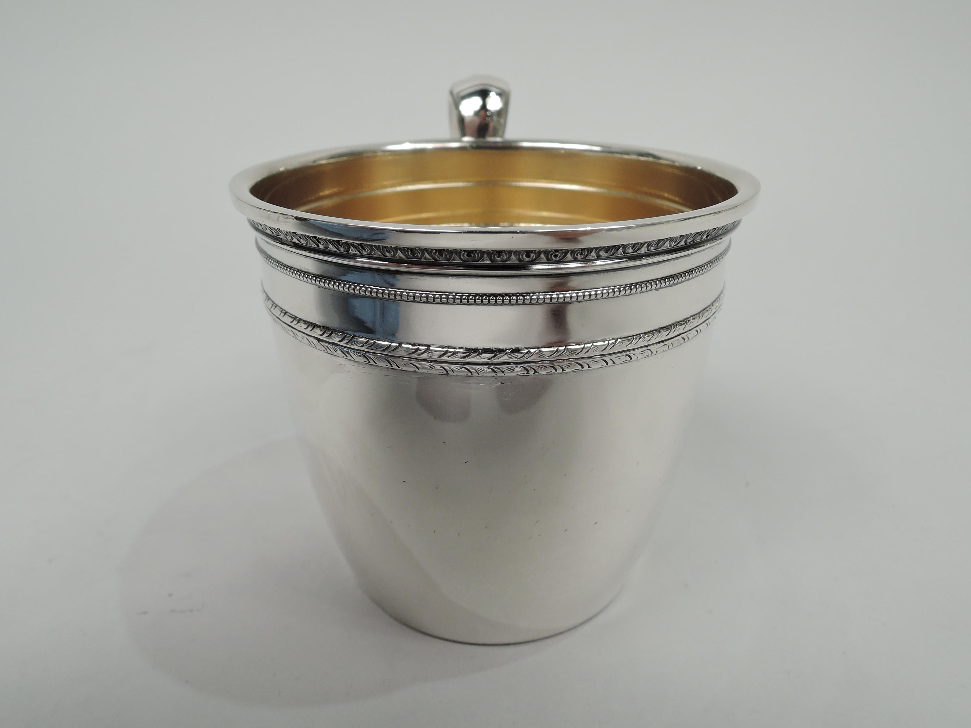 Edgeworth sterling silver baby cup. Made by Gorham in Providence in 1923. Gently curved and tapering sides and leaf-mounted and capped high-looping handle. Neoclassical ornamental bands including leaf and dart and beading. Gilt-washed interior.