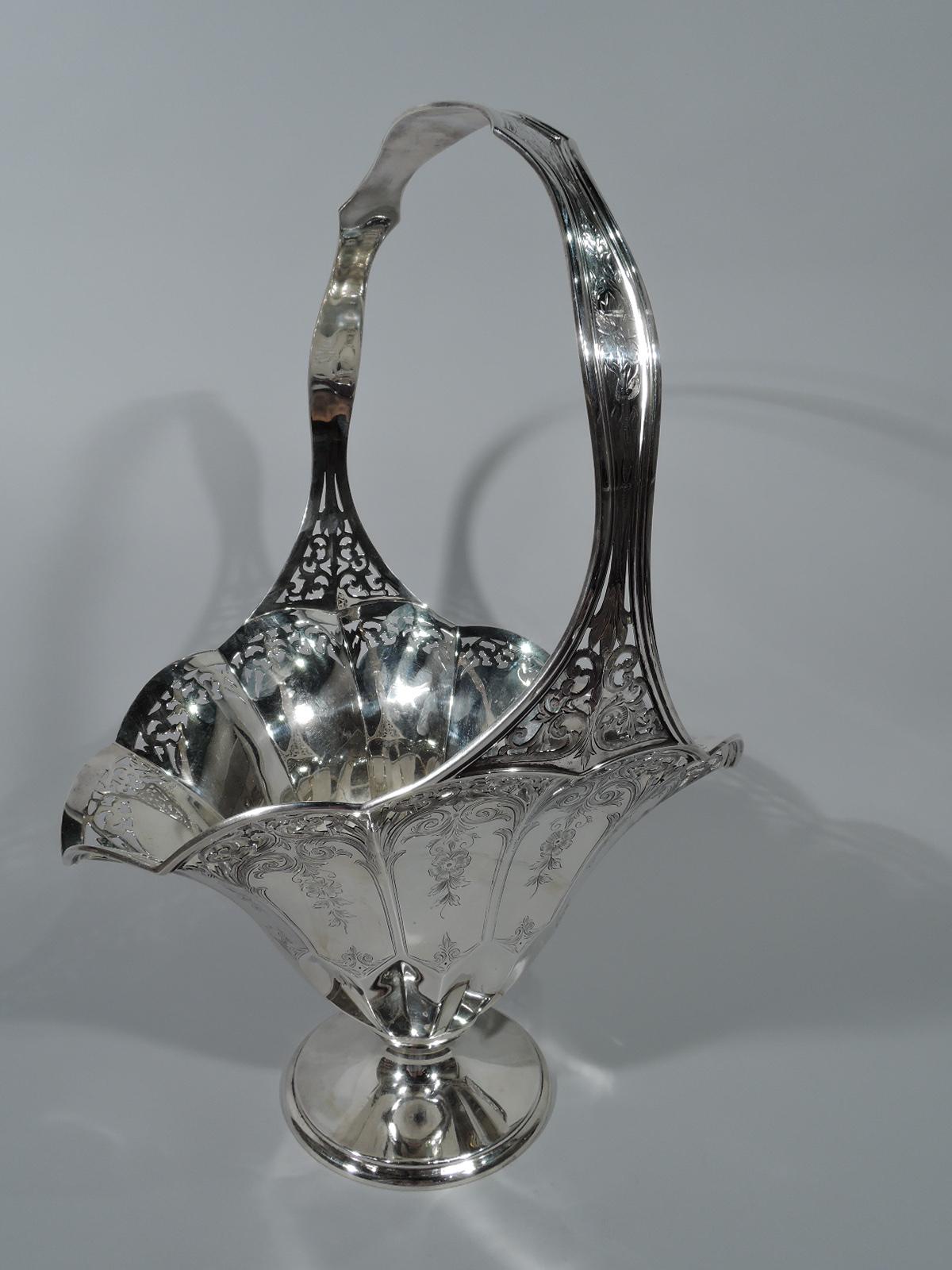 Edwardian sterling silver basket. Made by Gorham in Providence in 1915. Faceted and tapering with wide oval mouth, petal rim, shaped stationary handle, faceted bottom, and circular foot. A distinctive updating of a traditional form. On exterior