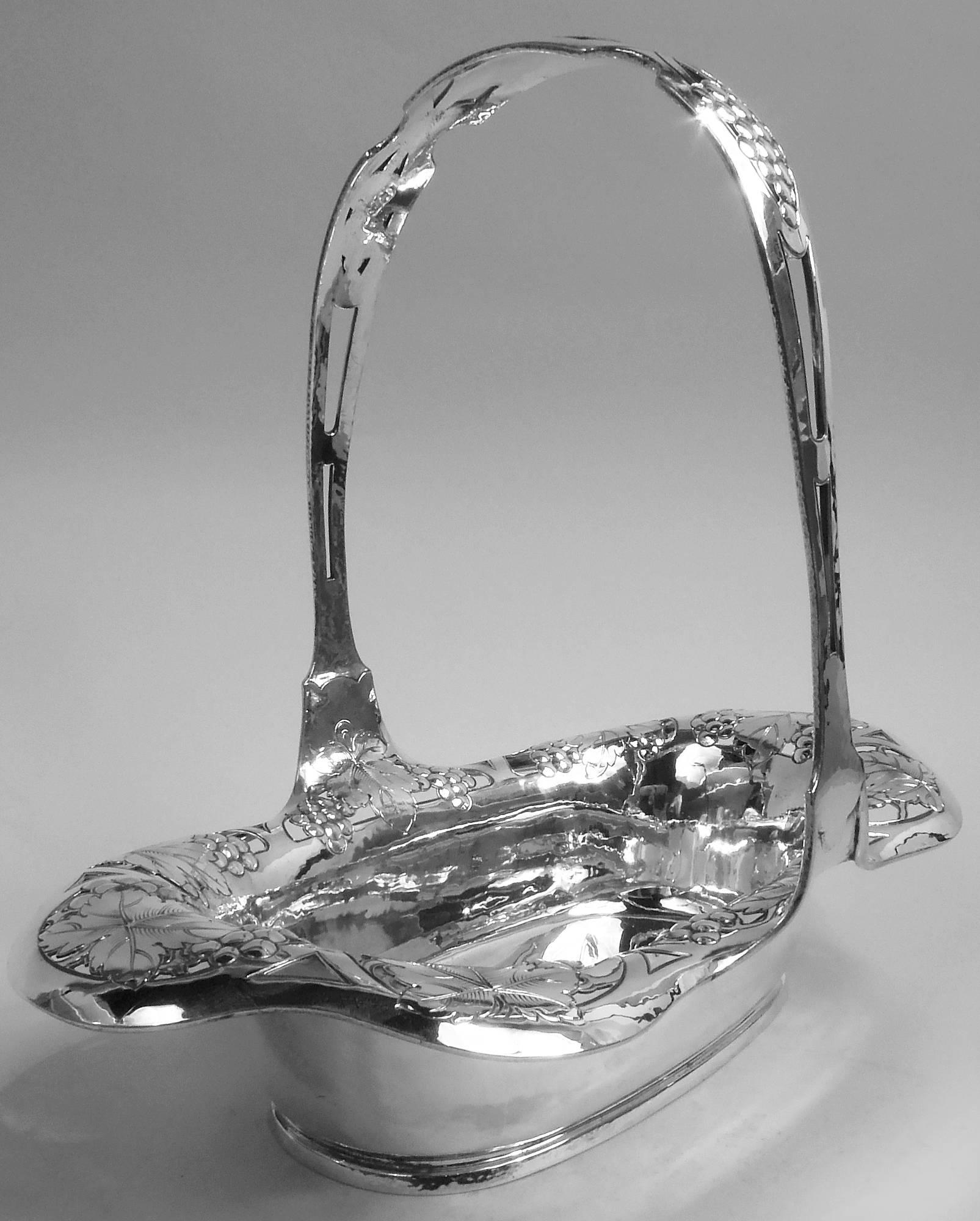 Panier édouardien en argent sterling de style Art nouveau. Fabriqué par Gorham à Providence, vers 1910. Bordure à volutes et rabattue avec des grappes de raisin et des feuilles gravées se chevauchant dans des cadres à lunette ouverte. Poignée