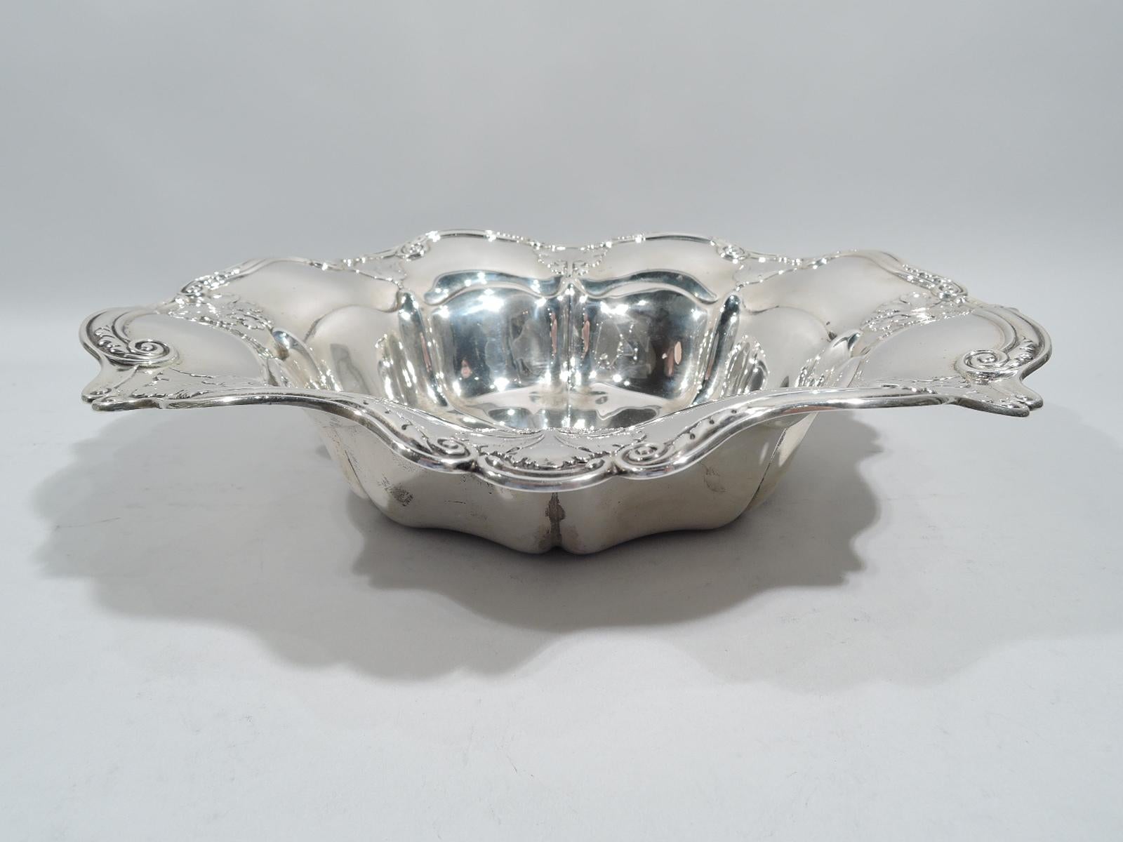 Turn-of-the-century Edwardian classical sterling silver bowl. Made by Gorham in Providence. Round with lobed and concave sides. Wavy shoulder with applied leaves and flowers, and scrolled rim. Well center engraved with interlaced script monogram.