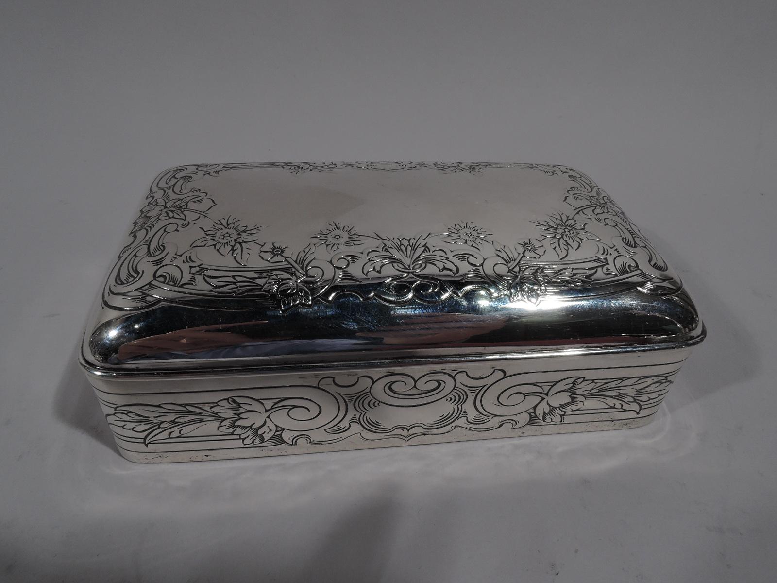 Edwardian Classical sterling silver jewelry box. Made by Gorham in Providence in 1913. Rectangular with straight sides and curved corners. Cover hinged and curved with molded rim. Box has wrapround linear bands terminating at front in volute