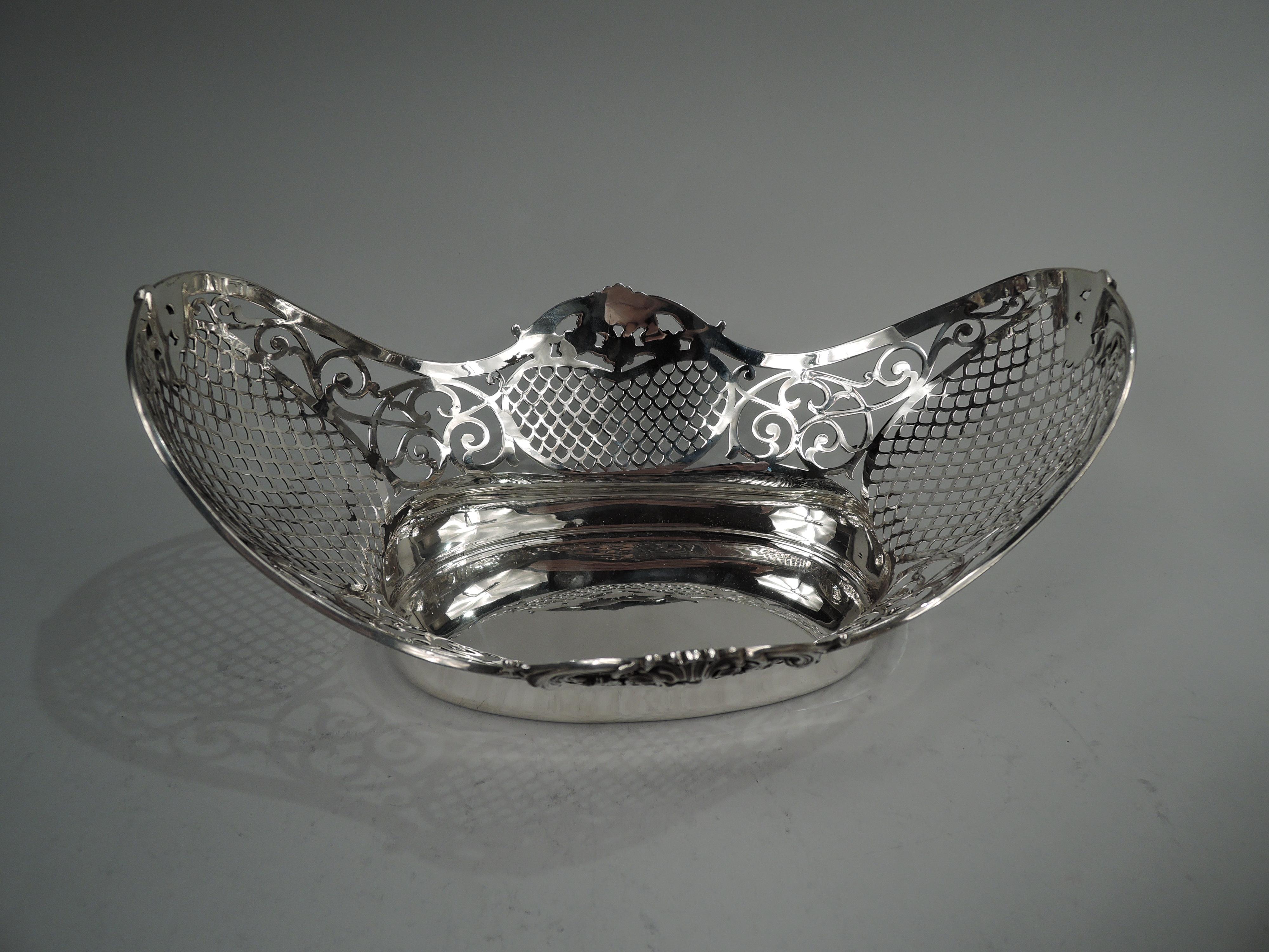 Edwardian Classical sterling silver bowl. Made by Gorham in Providence in 1906. Solid oval well and curved sides with pierced diaper and open leafing scrollwork. Rim reeded and steeply asymmetrical with applied shells, scrolls, and flowers. Fully