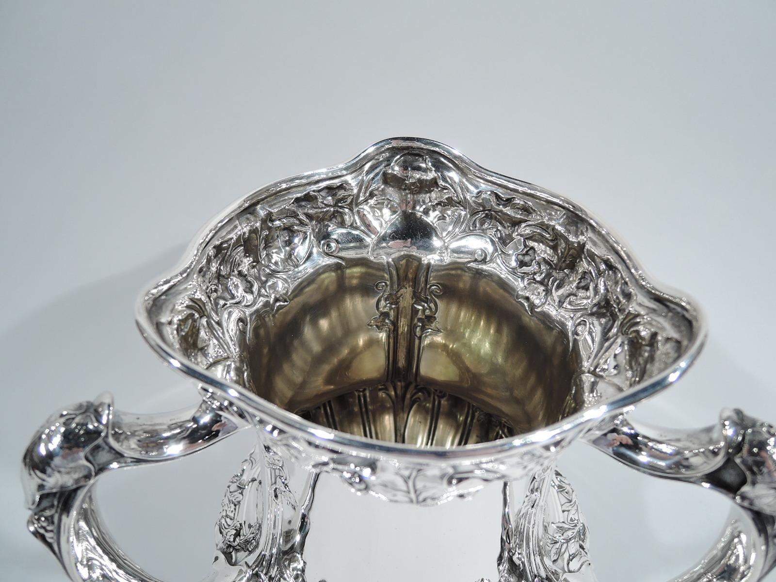 Edwardian sterling silver loving cup. Made by Gorham in Providence in 1907. Bellied urn with 3 leaf-capped handles and domed foot. Scrolled and molded rims, and chased leaves and scallop shells. Top entwined with victor’s laurels. Dynamic