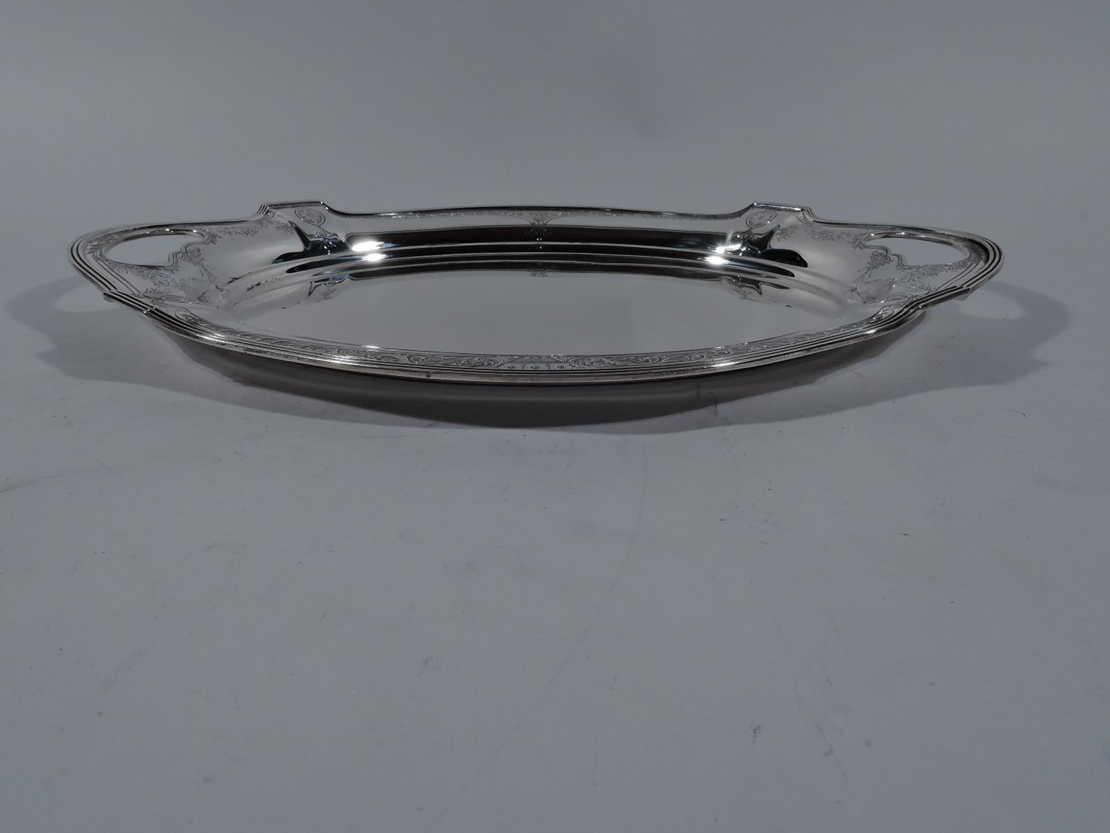 Edwardian Regency sterling silver platter tray. Made by Gorham in Providence in 1915. Oval well with paneled curvilinear shoulder and reeded rim. Cutout oval end handles. Flower baskets, paterae, garlands, and leafing scrolls engraved on shoulder.