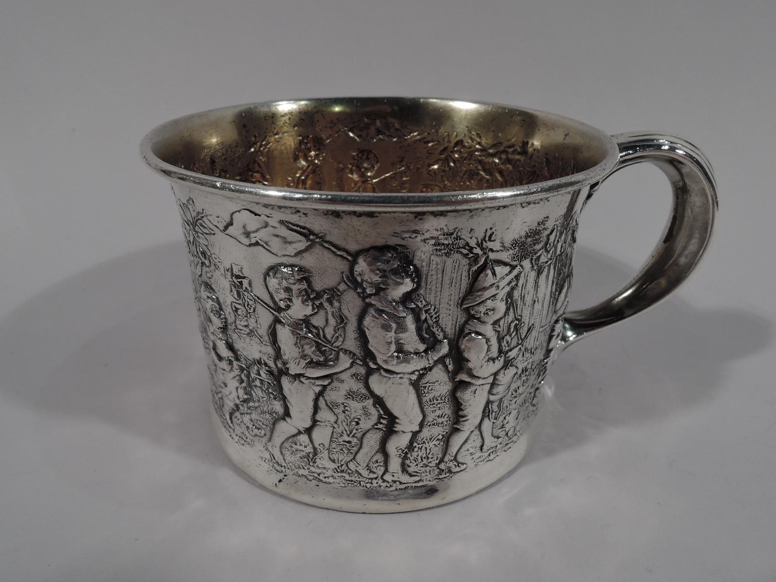 Edwardian sterling silver pictorial baby cup. Made by Gorham in Providence, circa 1920. Straight sides and reeded C-scroll handle. Interior gilt washed. Chased scene of boy’s procession marching single file: The cavalry, in the person of a