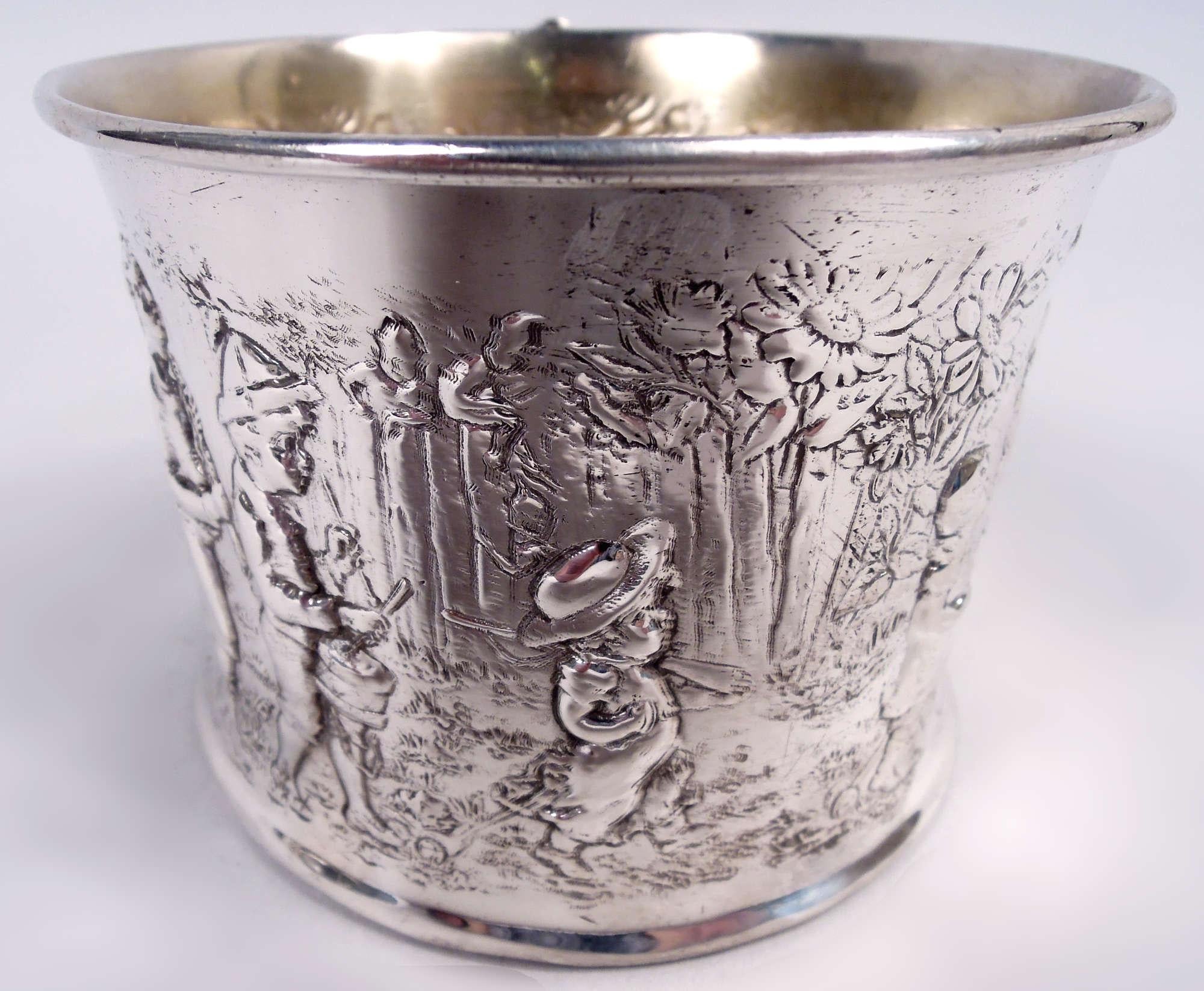 Edwardian sterling silver pictorial baby cup. Made by Gorham in Providence, ca 1920. Straight sides and reeded c-scroll handle. Interior gilt washed. On underside engraved interlaced script monogram.

Chased scene of boy’s procession marching single