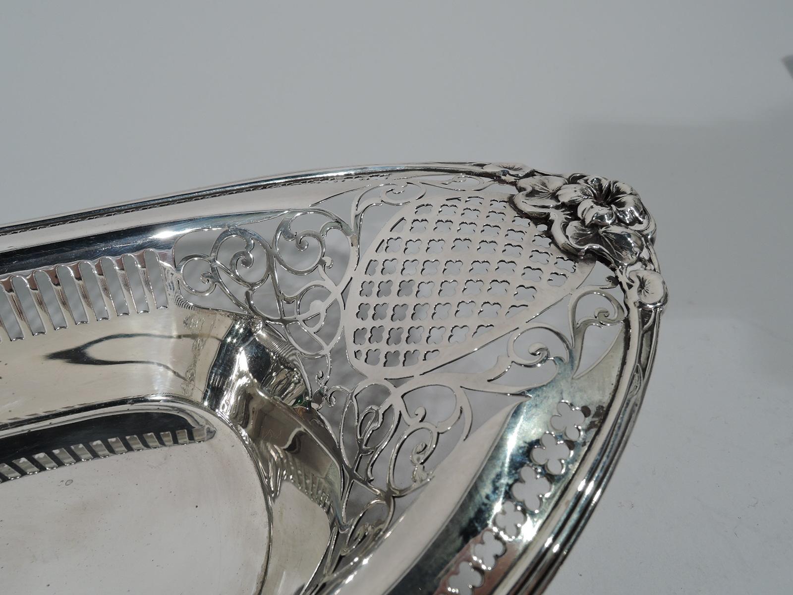 Edwardian sterling silver bread tray. Made by Gorham in Providence, circa 1900. Elongated oval with solid tubular well and pierced diaper, quatrefoils, scrolls, and colonnade. Pretty blossoms applied at ends. Hallmark includes no. A5324. Weight: