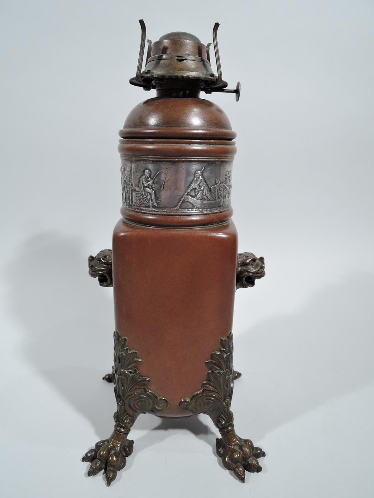 Japonesque mixed metal lamp base. Made by Gorham in Providence in 1882. Rectilinear copper body with bronze foo dog heads mounted to sides, and leaf-and-scroll corner mounts with bulgy talon supports. Domed inset top with low relief silver frieze