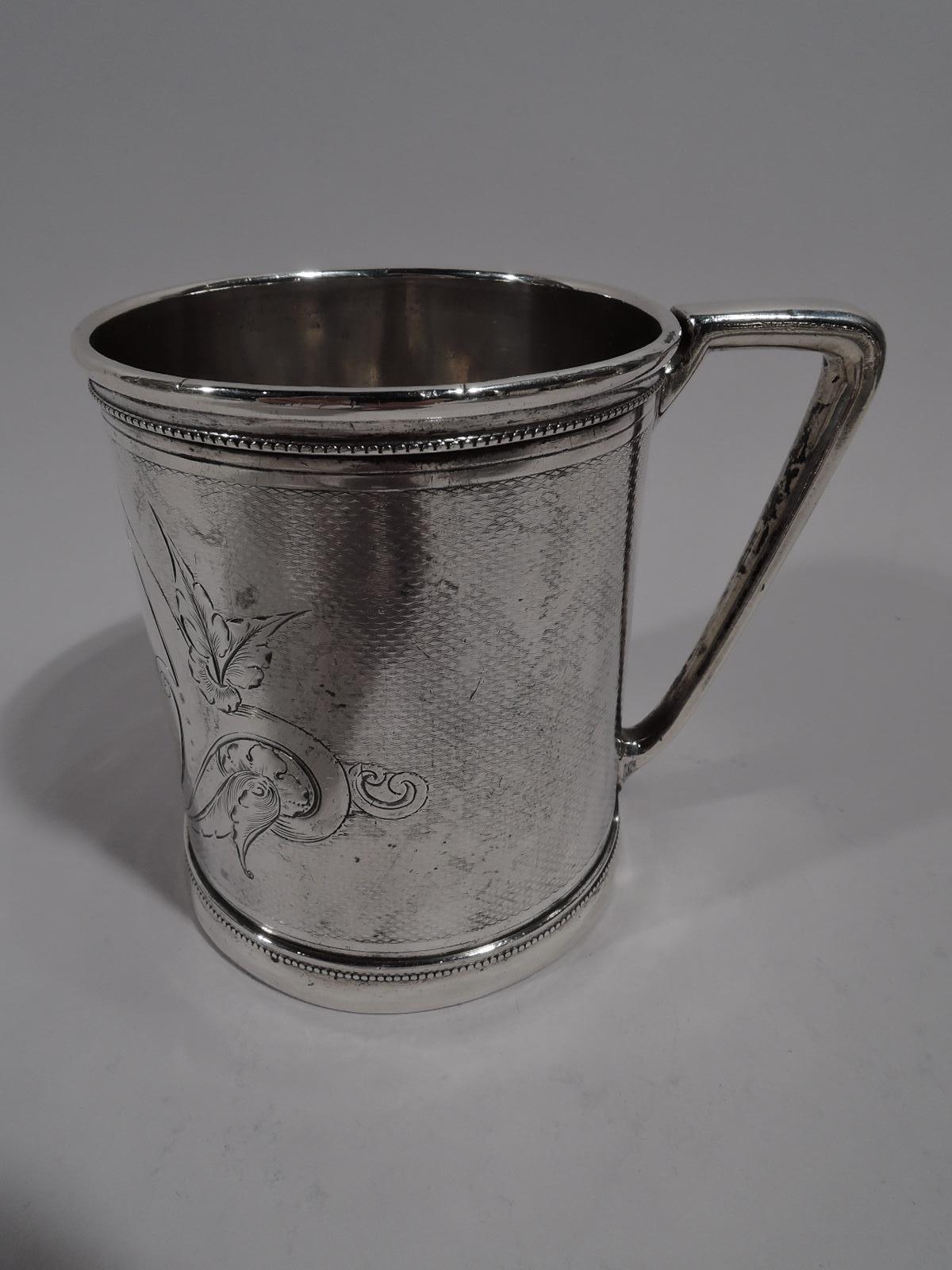 Modern Classical coin silver baby cup. Made by Gorham in Providence, circa 1865. Straight sides with skirted foot and bracket handle. Scrolled and leafy frame (vacant) on engine-turned wavy ground. Beading. Bold and sophisticated. Fully marked and