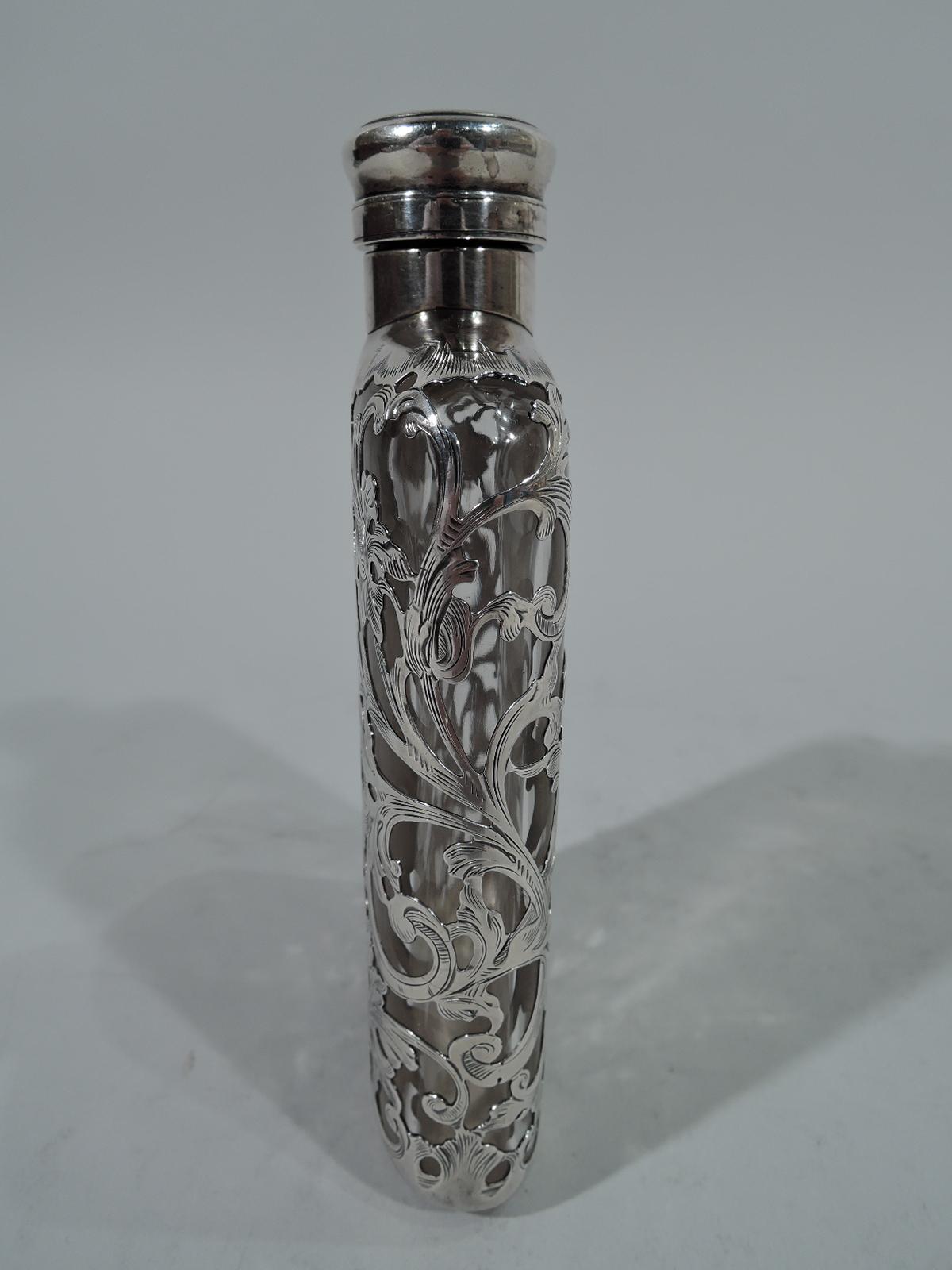 Turn-of-the-century glass flask with silver overlay. Made by Gorham in Providence. Clear glass with all-over silver leafy scrollwork heightened with engraving. On front strapwork cartouche engraved with interlaced script monogram. On back solid