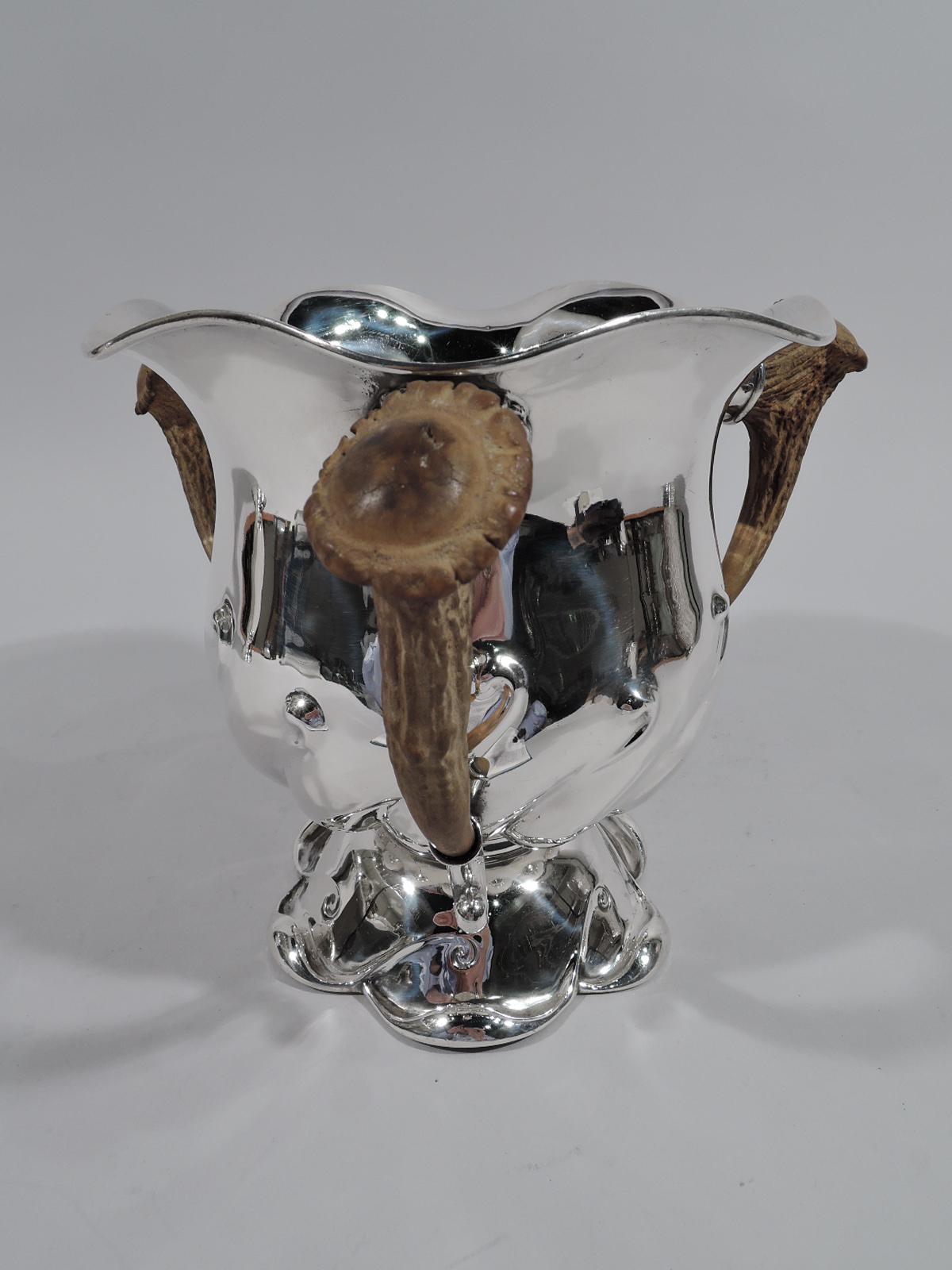 Big Game-era sterling silver alpha loving cup. Made by Gorham in Providence, circa 1890. Curved body with embossed twisted scrolls, wavy rim, and domed and scalloped foot with incised scrolls. Three antler handles in sterling silver mounts. Fully