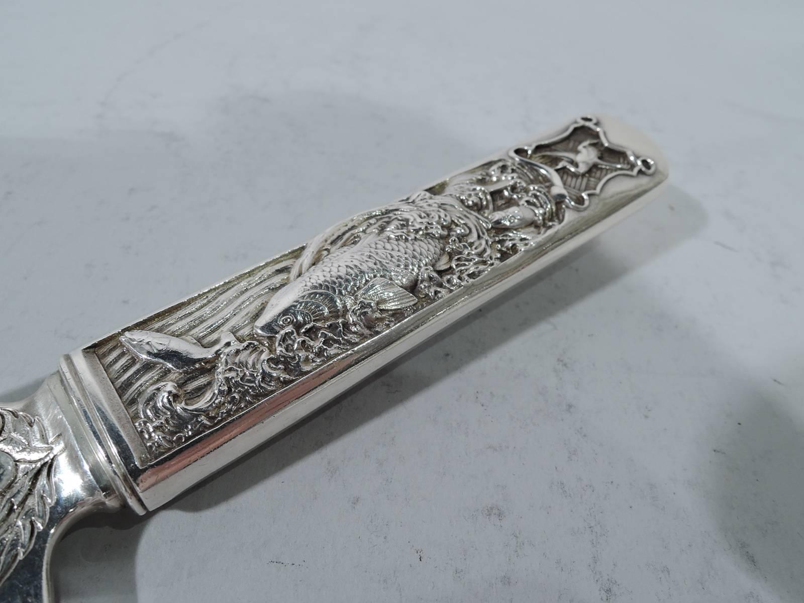 Japonesque sterling silver fish server in Hizen pattern. Made by Gorham in Providence. Rectilinear handle with flying crane, carp in wave, and flowers set in shaped frames and on wavy and patchwork grounds. Blade had scalloped top and engraved