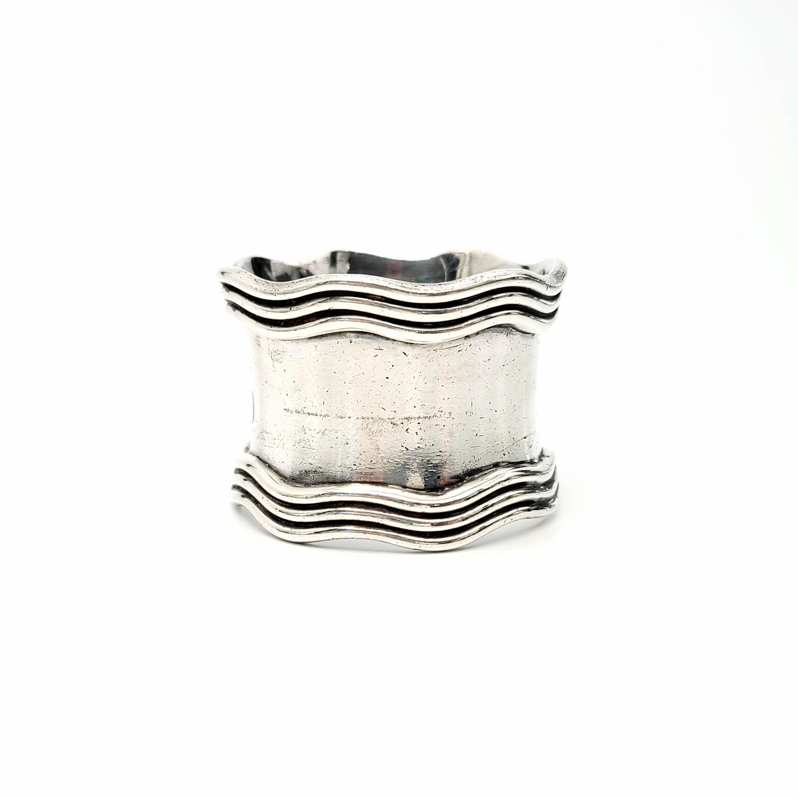 Antique Gorham sterling silver napkin ring.

Scalloped and ribbed edges on a polished ring with ornate monogram. The B hallmark dates this piece to 1869.

Monogram on the outside appears to be a WJJ. Monogram on inside of ring appears to be