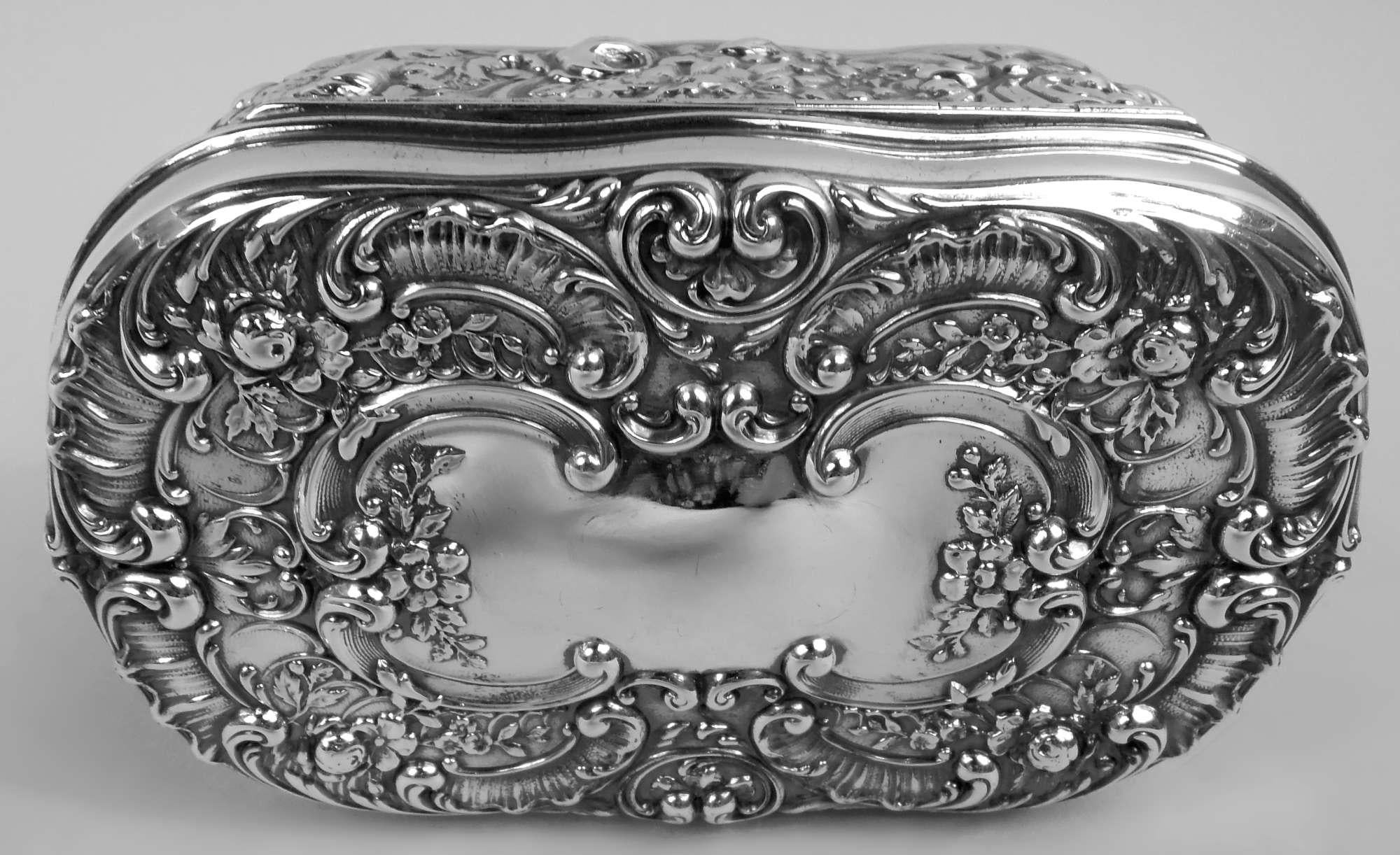 Victorian Classical sterling silver trinket box. Made by Gorham in Providence, ca 1900. Shaped and tubular. Cover hinged with molded rim. On top chased scroll and flower cartouche (vacant) surrounded by leafing scrolls and flowers; sides same. Fully