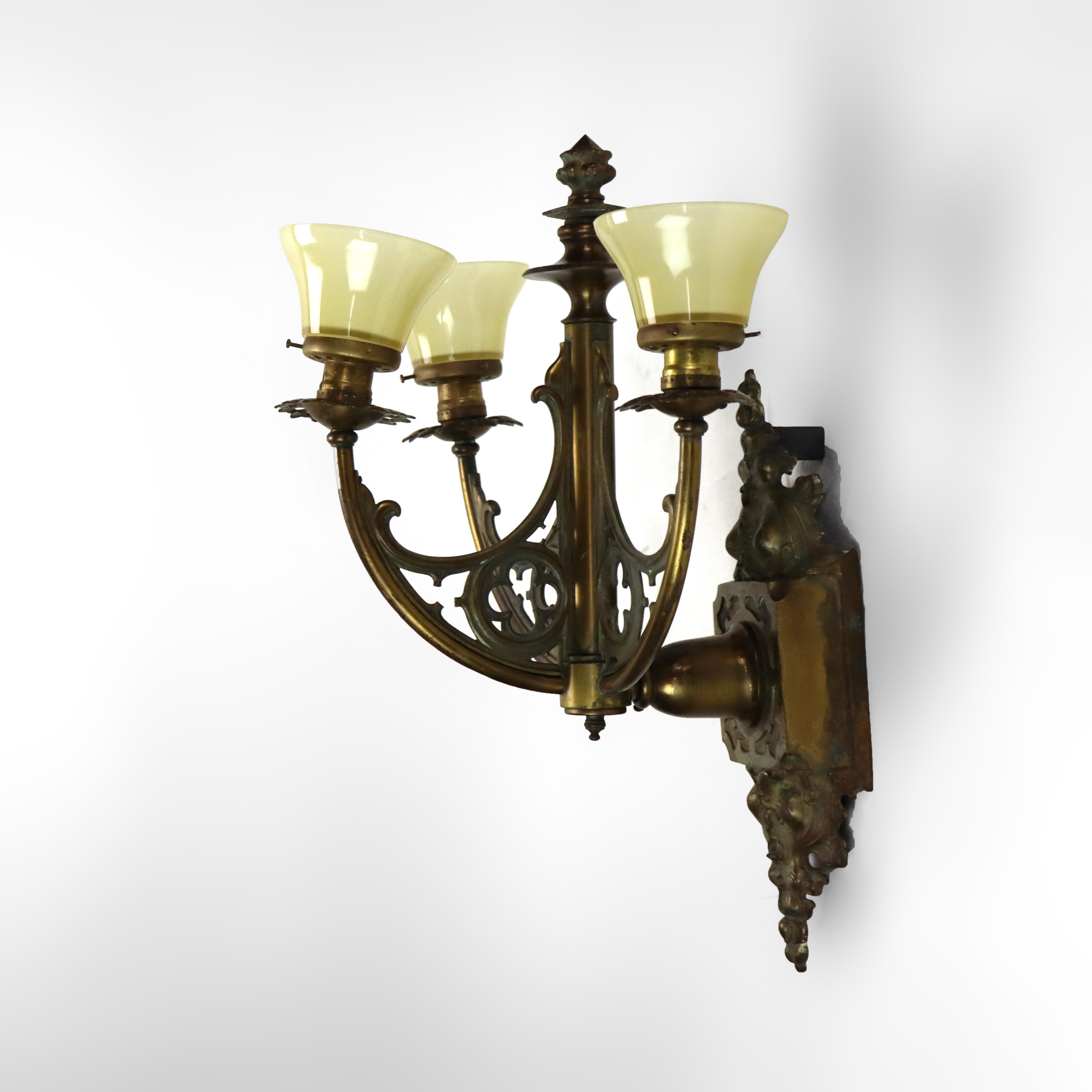 Applique murale ancienne en bronze gothique à trois lumières avec abat-jour en verre d'art jaune, vers 1920.   
21 3/4