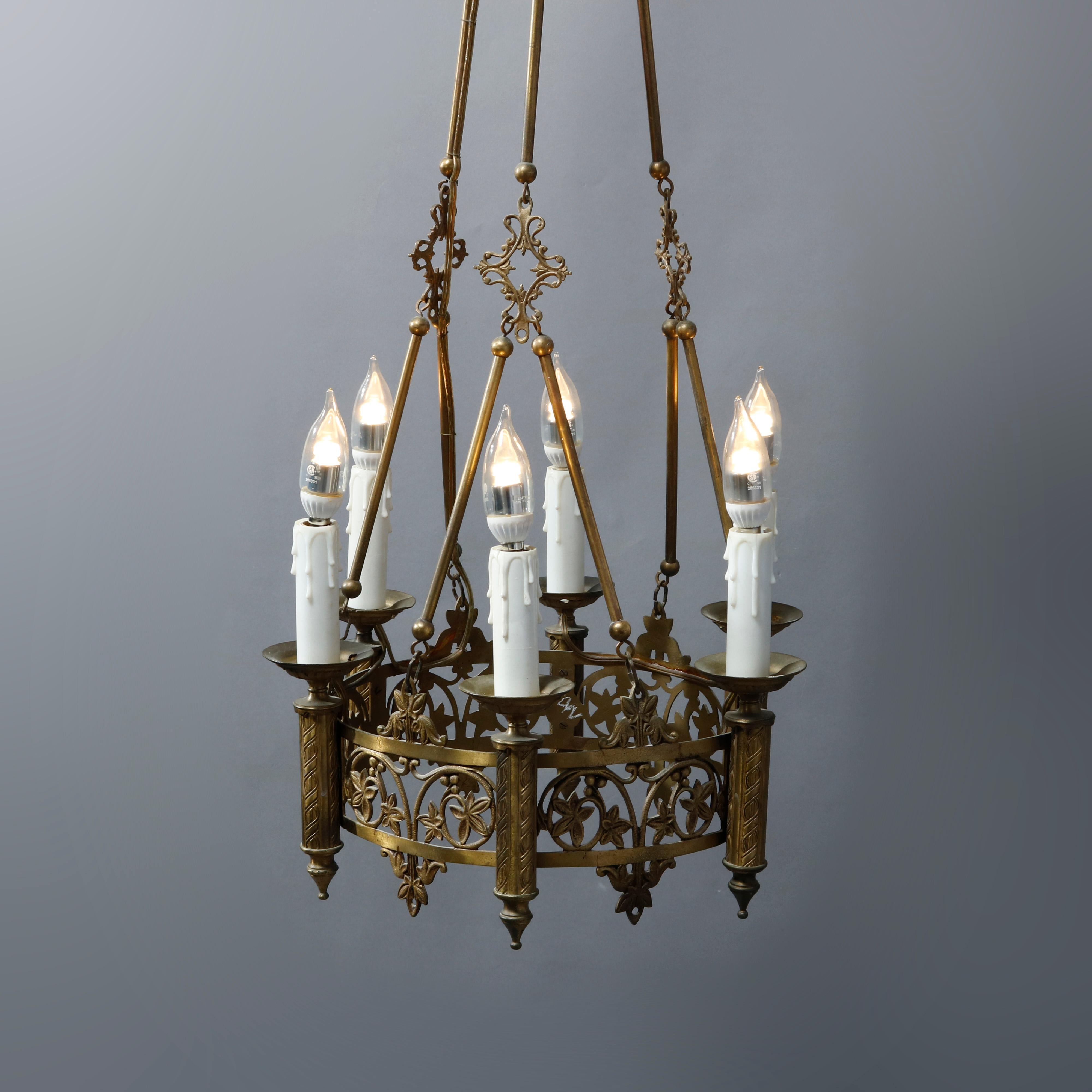 An antique Gothic hanging chandelier offers cast bronze pierced scroll and foliate filigree frame with six candle lights and drop bar chain with crown form cap, c1900.

Measures: 44.5
