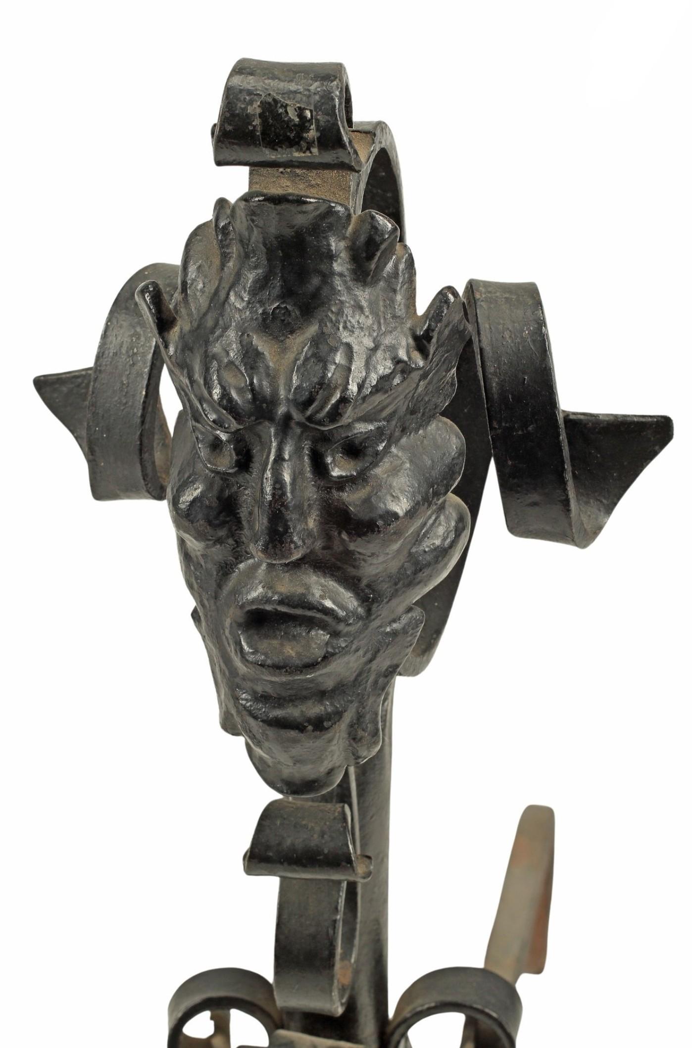 A pair of large and fanciful Victorian Gothic Revival style wrought iron andirons, each with a grotesque mask.

What better place to showcase your devil face than in front of a blazing fireplace? These fantastic sculptural neo-gothic andirons