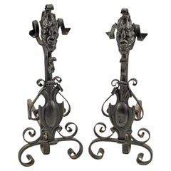 Andirons gothiques anciens en fer forgé avec masque grotesque et volutes