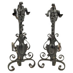 Andirons gothiques anciens en fer forgé avec masque grotesque et volutes 