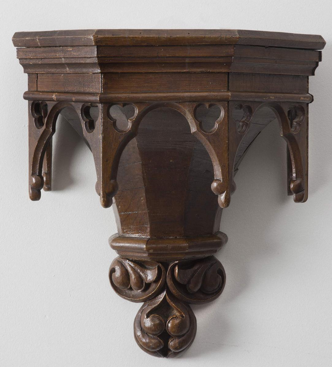 Large pine carved shelf wall bracket in the Gothic taste, the five-sided molded frieze above five arched elements enclosing trefoil designs. The pendant is in a carved trefoil design.