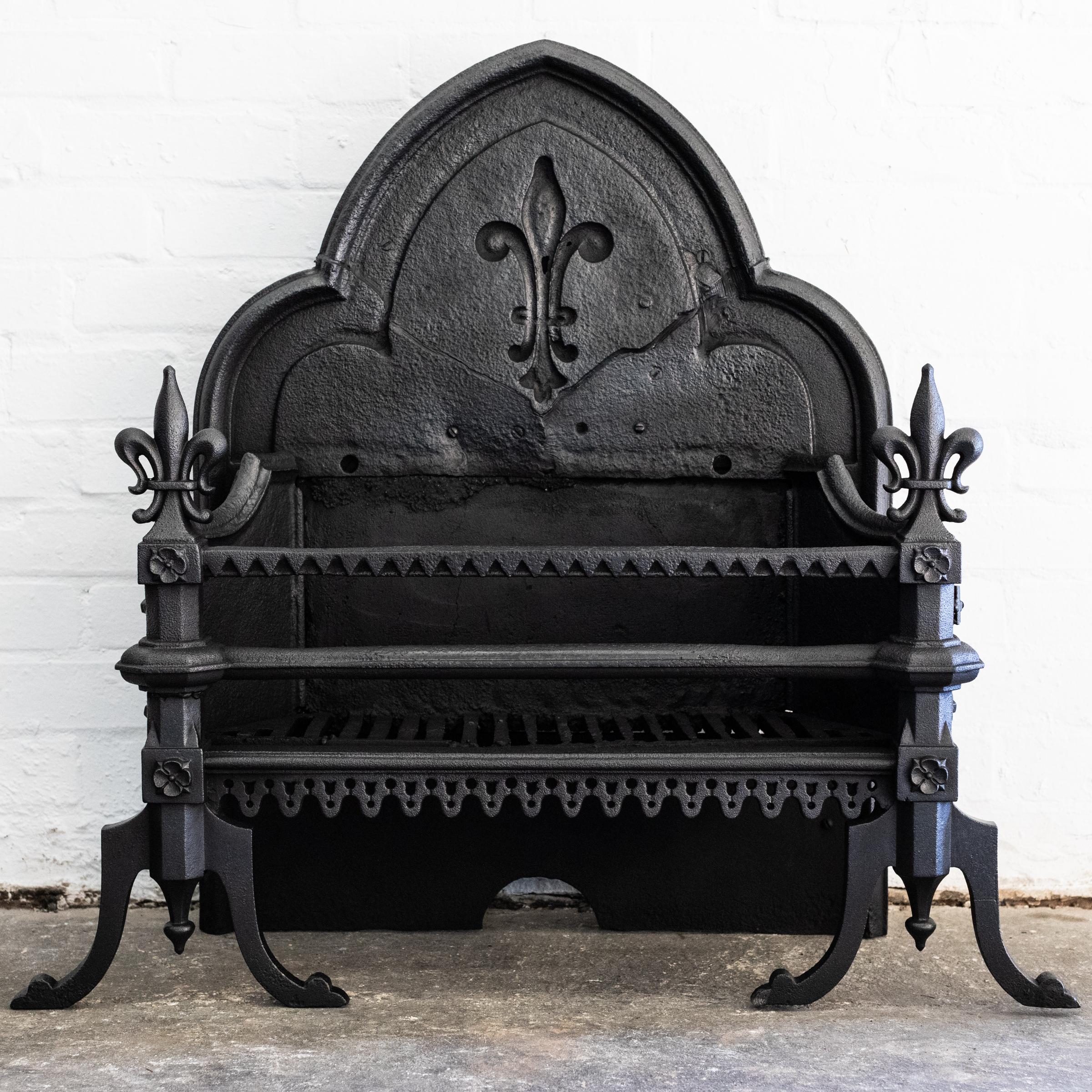 Questo grande camino in ghisa in stile gotico-revival ha un alto schienale a doppio arco con dettagli d'epoca.

Il pezzo si erge fiero su sostanziosi stendardi, ciascuno dei quali è sormontato da un grande Fleur De Lys, che viene ripreso sulla