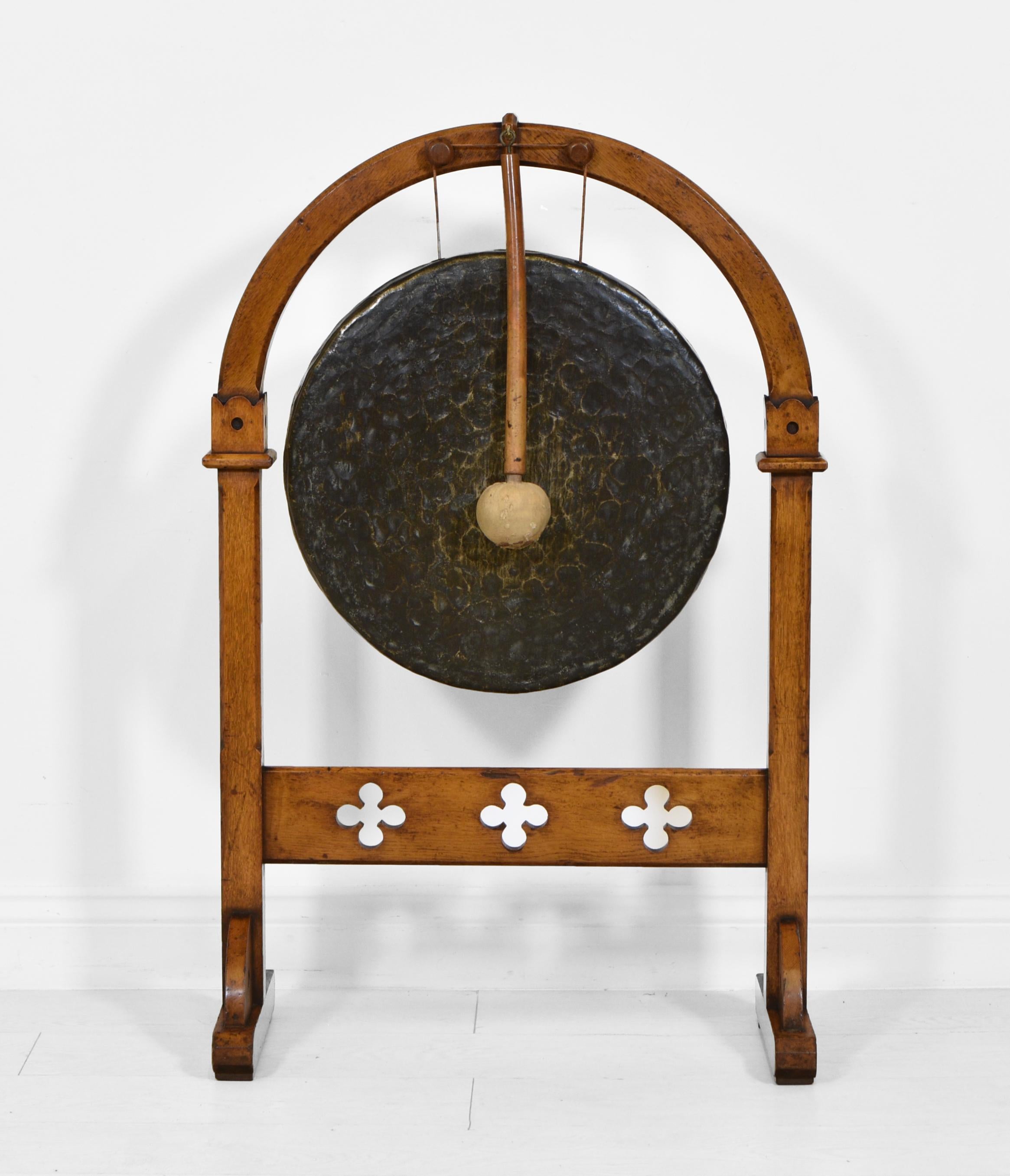 A Victorian period Gothic revival golden oak and brass dinner gong with beater. Circa 1880.

The oak frame has an arched top and chamfered uprights. The cross stretcher has quatrefoil pierced decoration. The oak frame does has scuff marks and