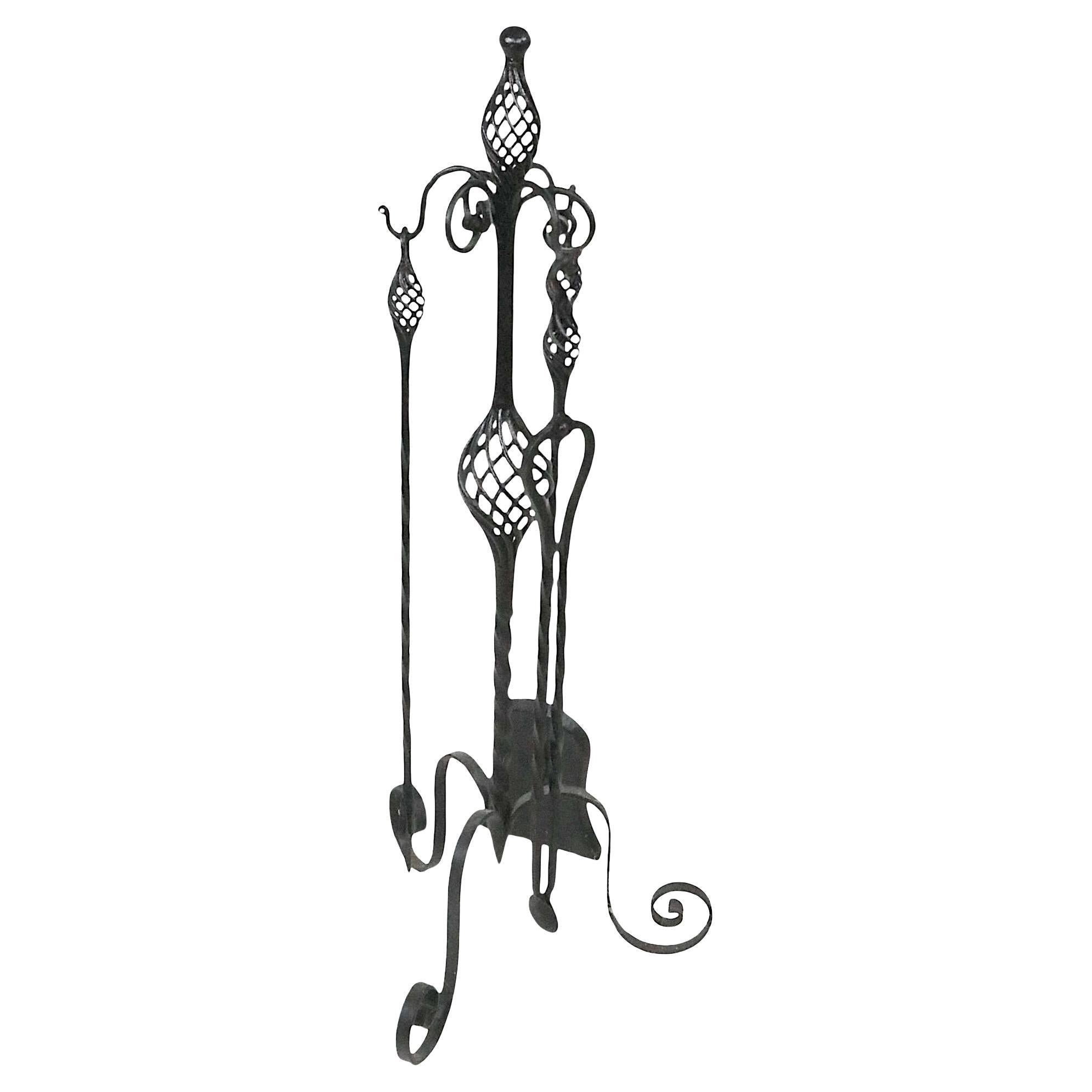 Unusual antique wrought iron four piece fireplace tool set consisting of a poker, shovel, tongs, and stand. The tools and stand feature openwork twisting wrought beehive form details, the stand has wrought iron curlicue feet. 
  All piece are in