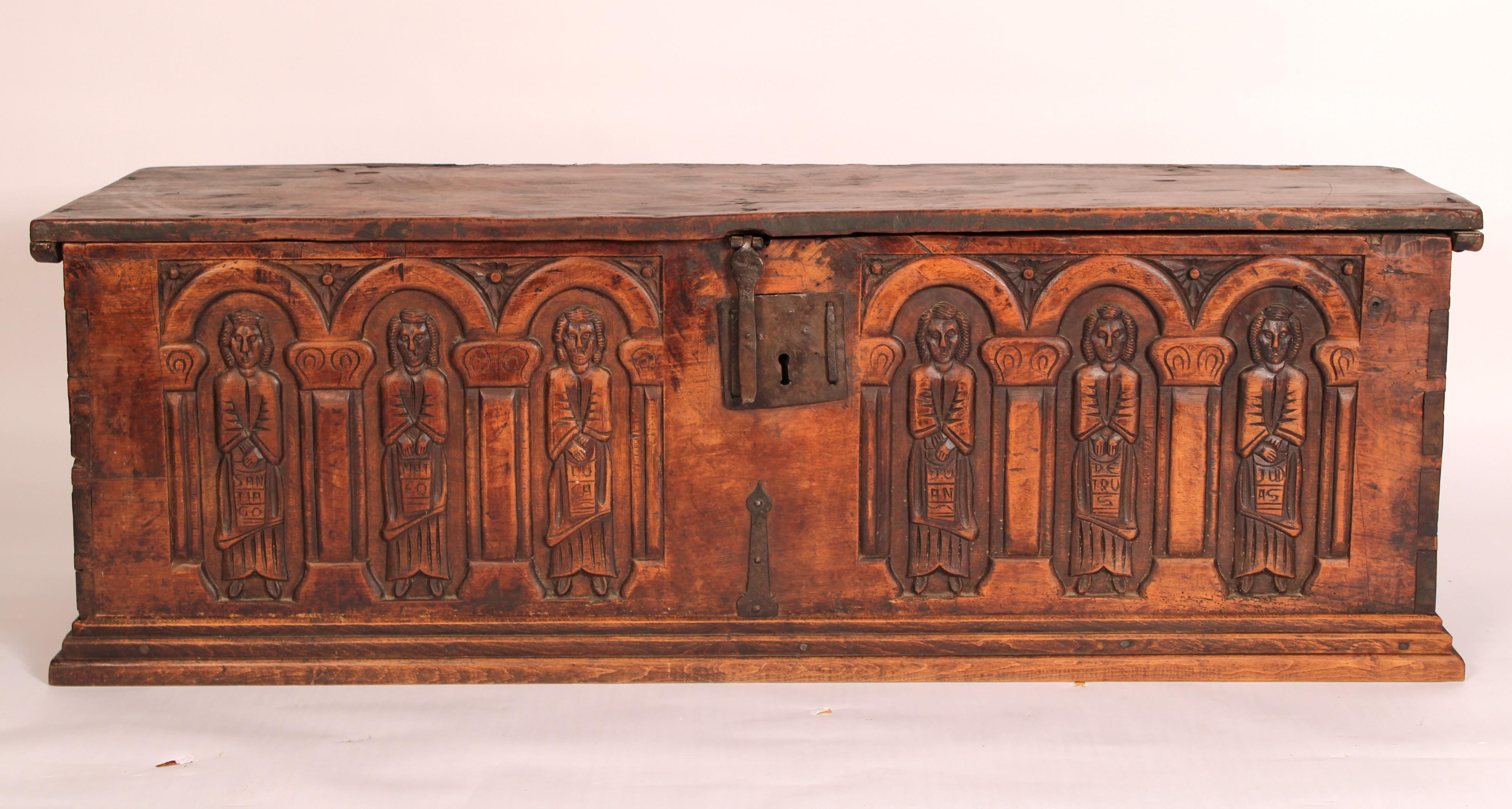 Continental gothic style elm trunk, early 19th century. With a hinged single board rectangular top, the front of the trunk with 6 carved gothic style figures and an old iron lock. The front and sides of the trunk are joined by dove tail