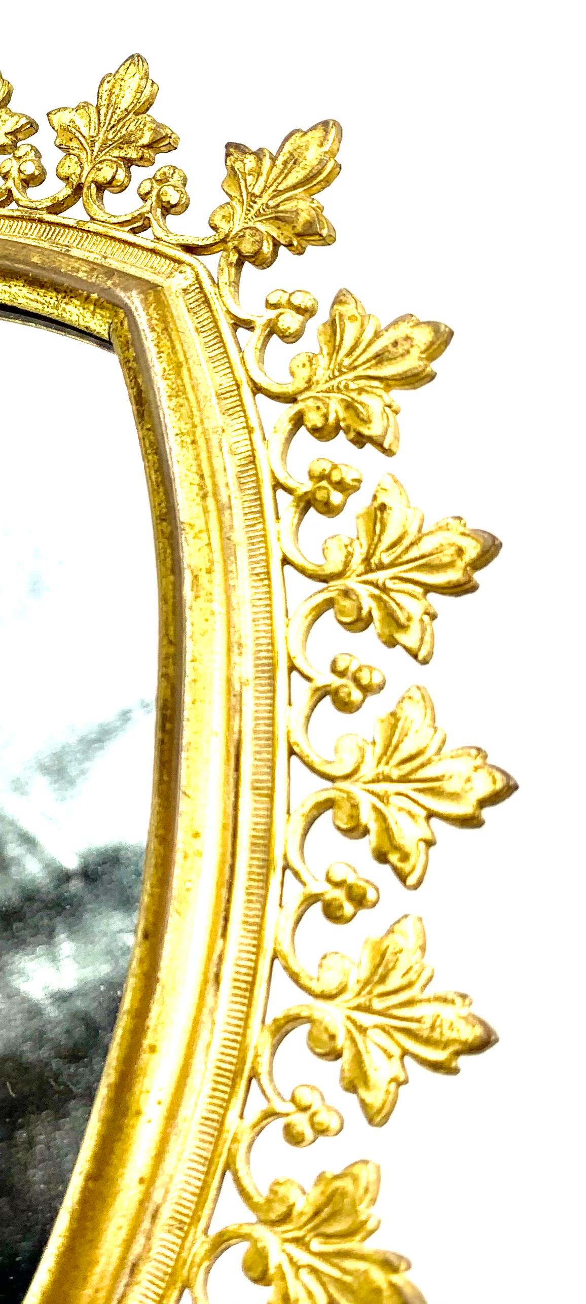 Eleganter und stilvoller Schminkspiegel aus vergoldeter Bronze im gotischen Stil. 
Frankreich, 19. Jahrhundert
Schöne antike Goldpatina, feine Details, ungewöhnliches Blatt- und Beerenmuster. Die wohlproportionierte, geschwungene Bogenform ist