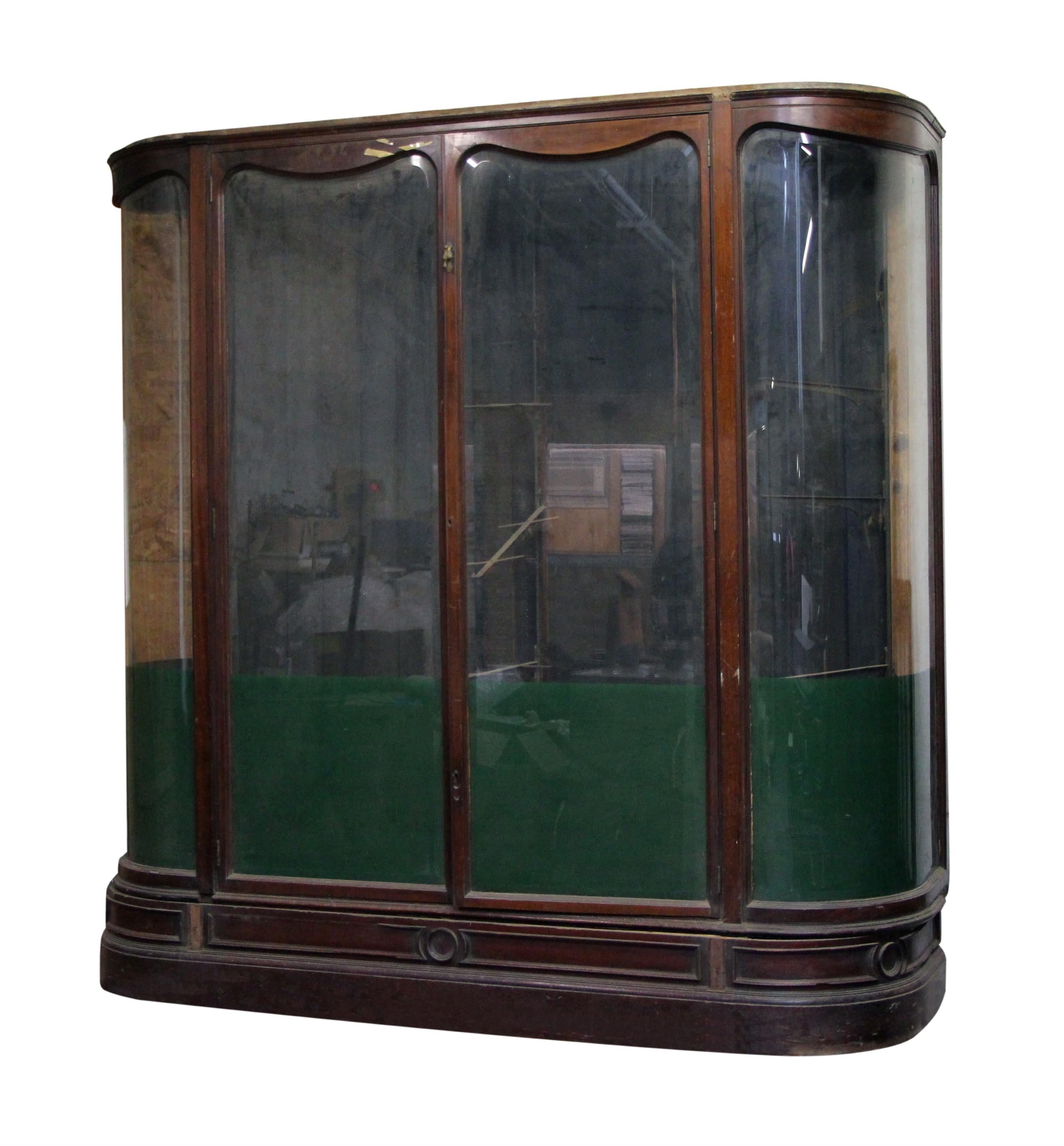Antique English showcase made of walnut with clear beveled glass windows and curved glass sides. The double doors open the front. Inside brackets for glass shelves are not included. Minor molding damages. Please note, this item is located in our