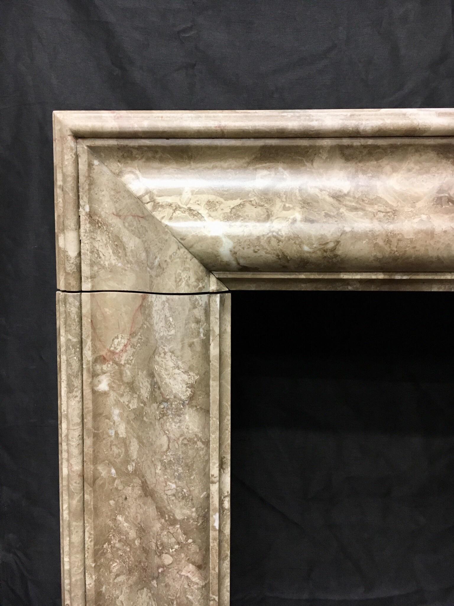 A large antique moulded bolection fireplace surround in a beige/grey Grand Napoleon Mouchette Marble, raised on square foot blocks. Together with its integral moulded fender, this piece would suit both, a period, or contemporary
