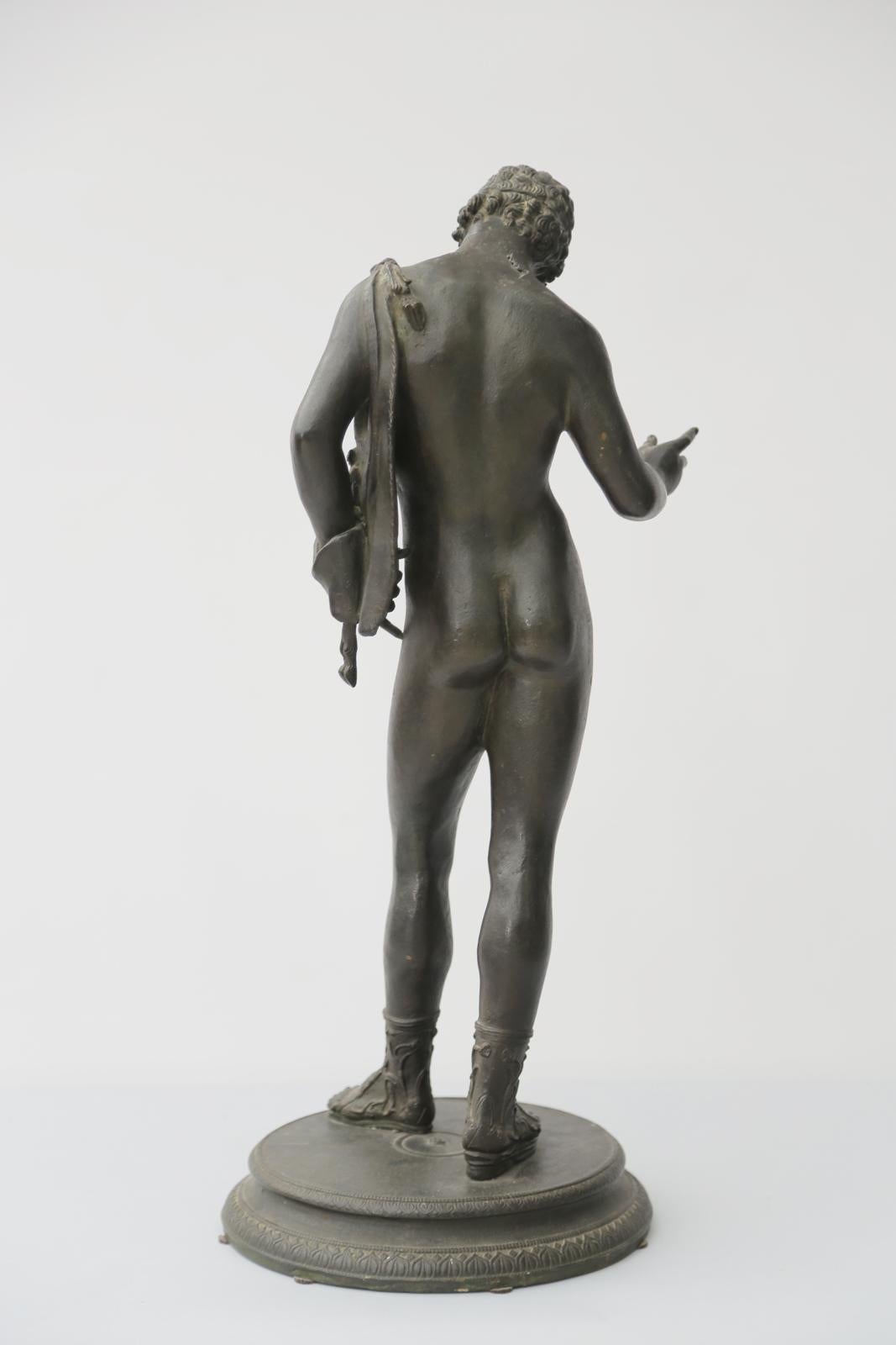 Sculpture en bronze gréco-romaine de Narcisse, d'après la sculpture originale exhumée en 1862 à Pompéi. La figure en bronze patiné vert représente le fils mythologique du dieu fleuve Cephissus et de la nymphe Liriope, posant debout, nu, portant des