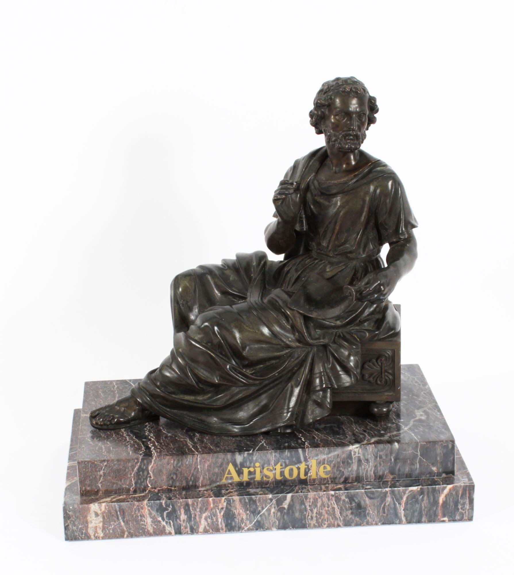 An elegant French Grand Tour bronze figure of Aristotle, dating from the early 19th century.
 
The robed bearded philosopher is holding a stylus and a scroll and turning ad sinistram, while seated on a pedestal ornamented with anthemion relief