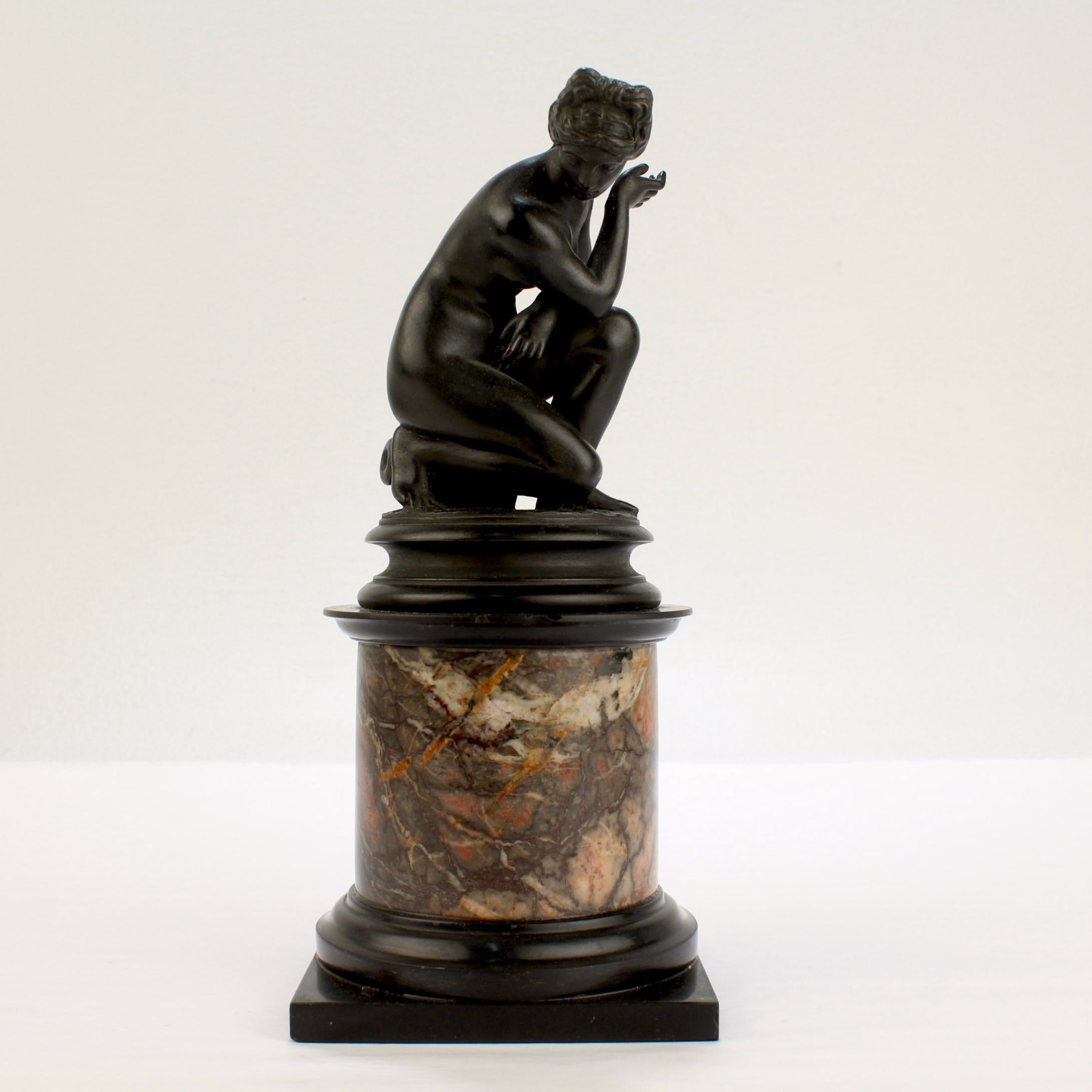 A very fine Grand Tour bronze sculpture.

Modeled after the 'Crouching Venus' by Giambologna.

Depicting Venus surprised at her bath with an overturned urn at her feet. Mounted on a slate and variegated marble plinth. 

Simply a wonderful
