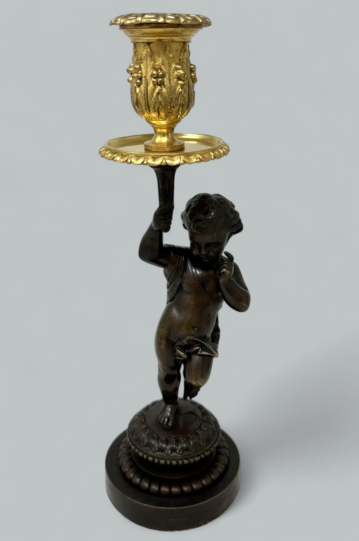 Impresionante Querubín clásico de bronce patinado fundido a cincel. Mediados y finales del siglo XIX.  

Sostiene en alto un único candelabro de ormolina, completo con su original bandeja de goteo de ajuste firme, que termina en una base circular de