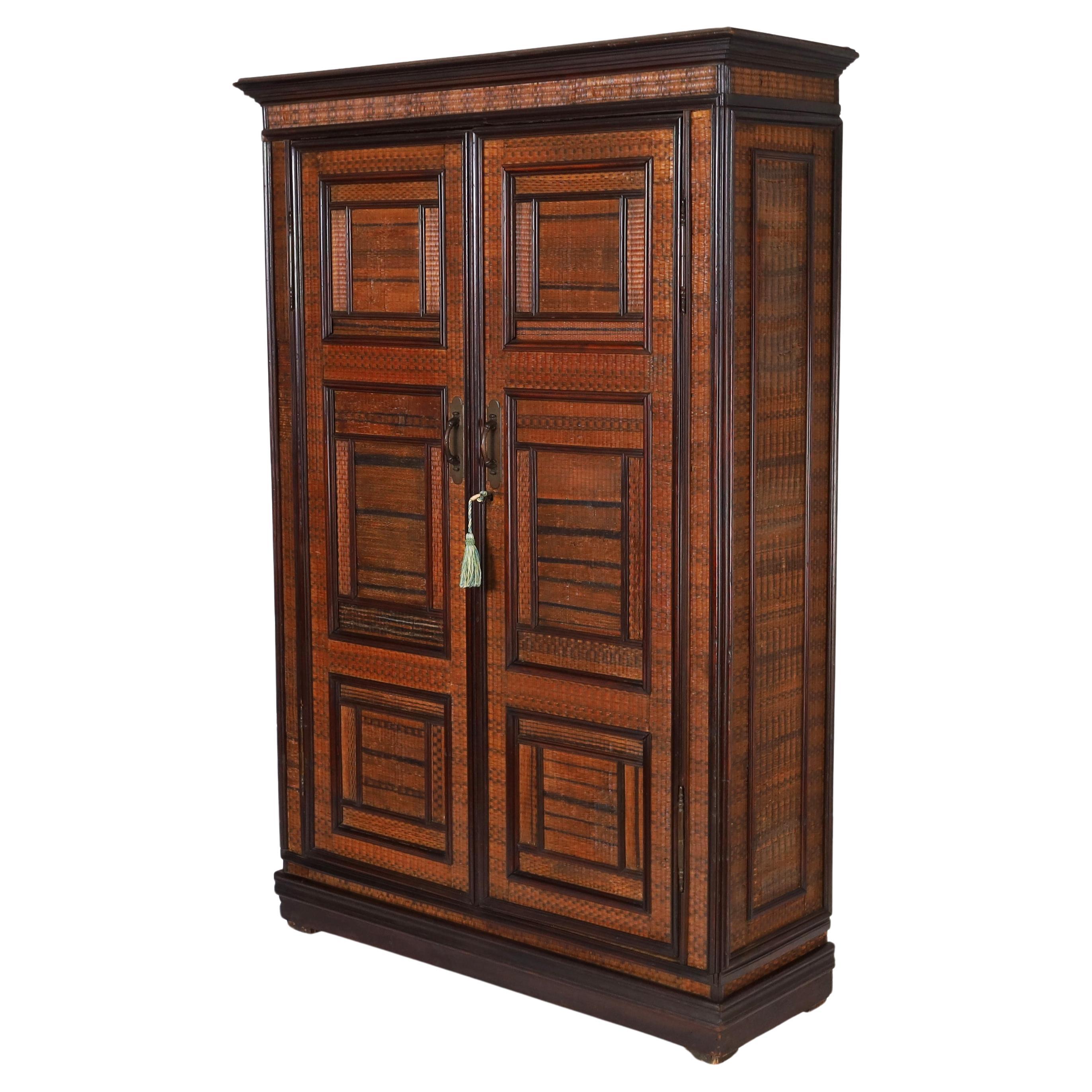 Impressive 19th century French cabinet with a case crafted in pine, having five adjustable shelves inside, and covered in woven reed featuring a cornice and geometric panels, bronze hardware, and block feet.