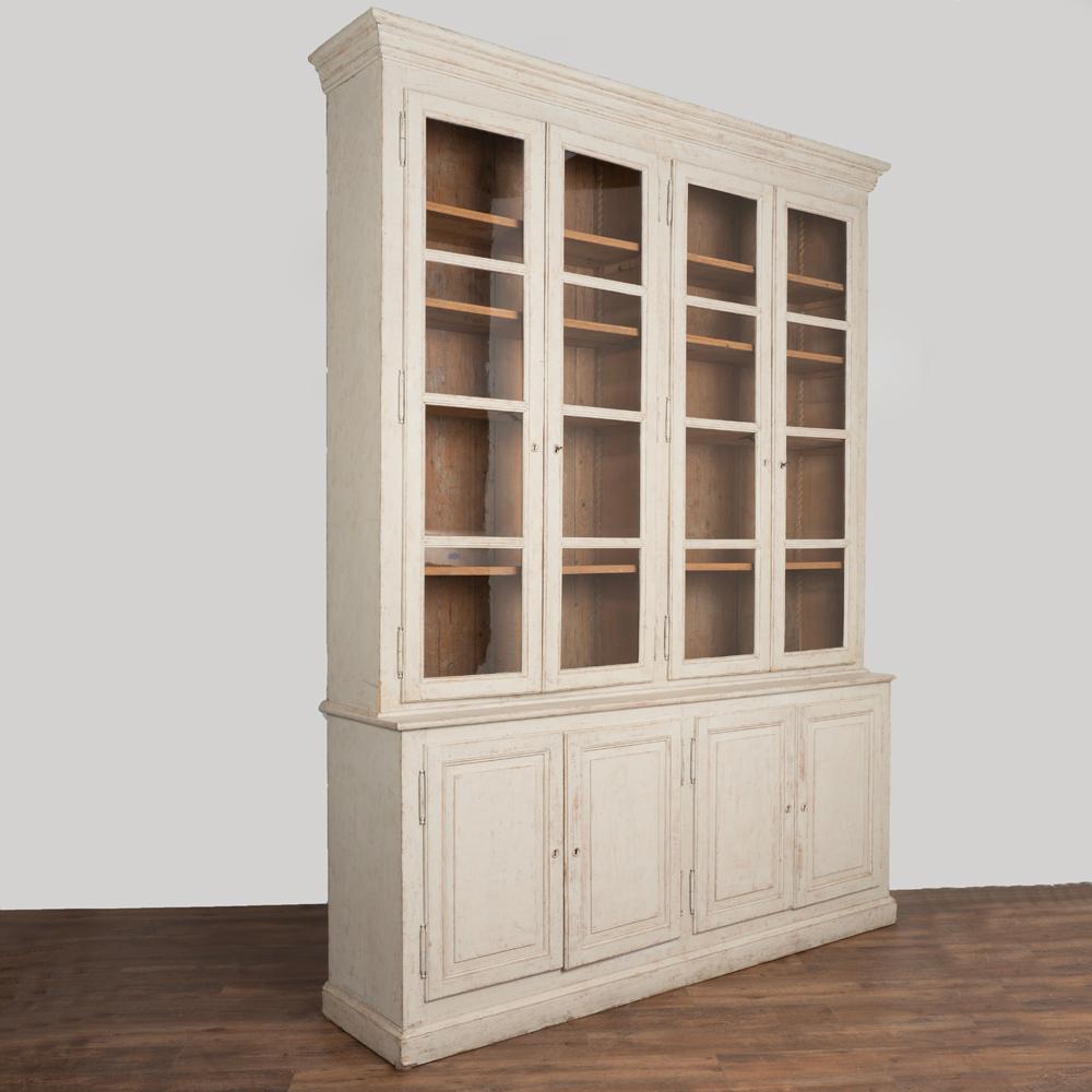 Elegant and stately 10' tall Swedish Gustavian country display cabinet or bookcase in two sections.
Newer professional painted finish in softly distressed light grey fitting the age and grace of this timeless piece.
Adjustable shelving and glass