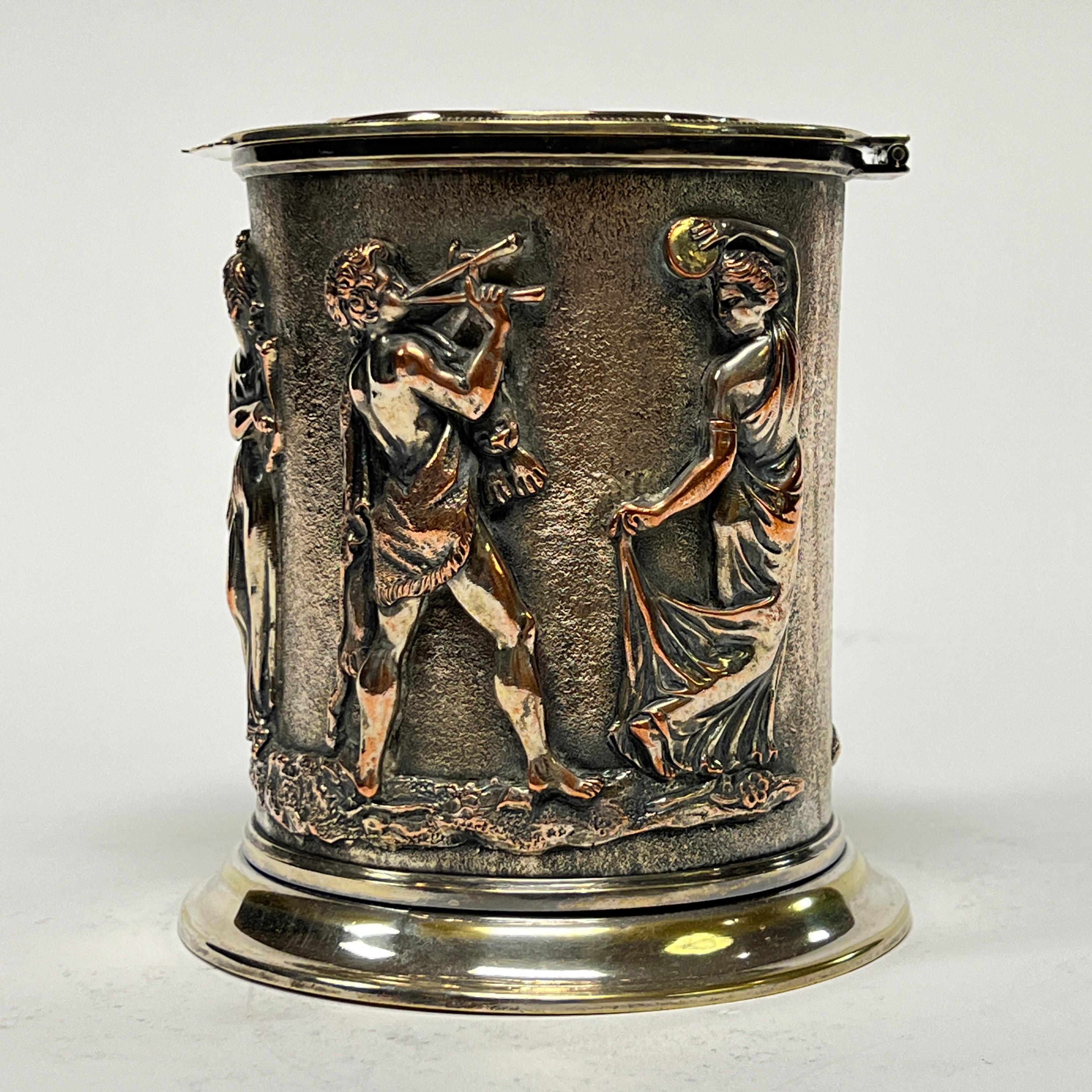 Finely crafted humidor in silvered copper featuring neoclassical figurative designs in relief, including muse with Cupid on lid and sides decorated with a procession of Greek or Roman figures.  6 3/4 inches tall and in very good condition. 