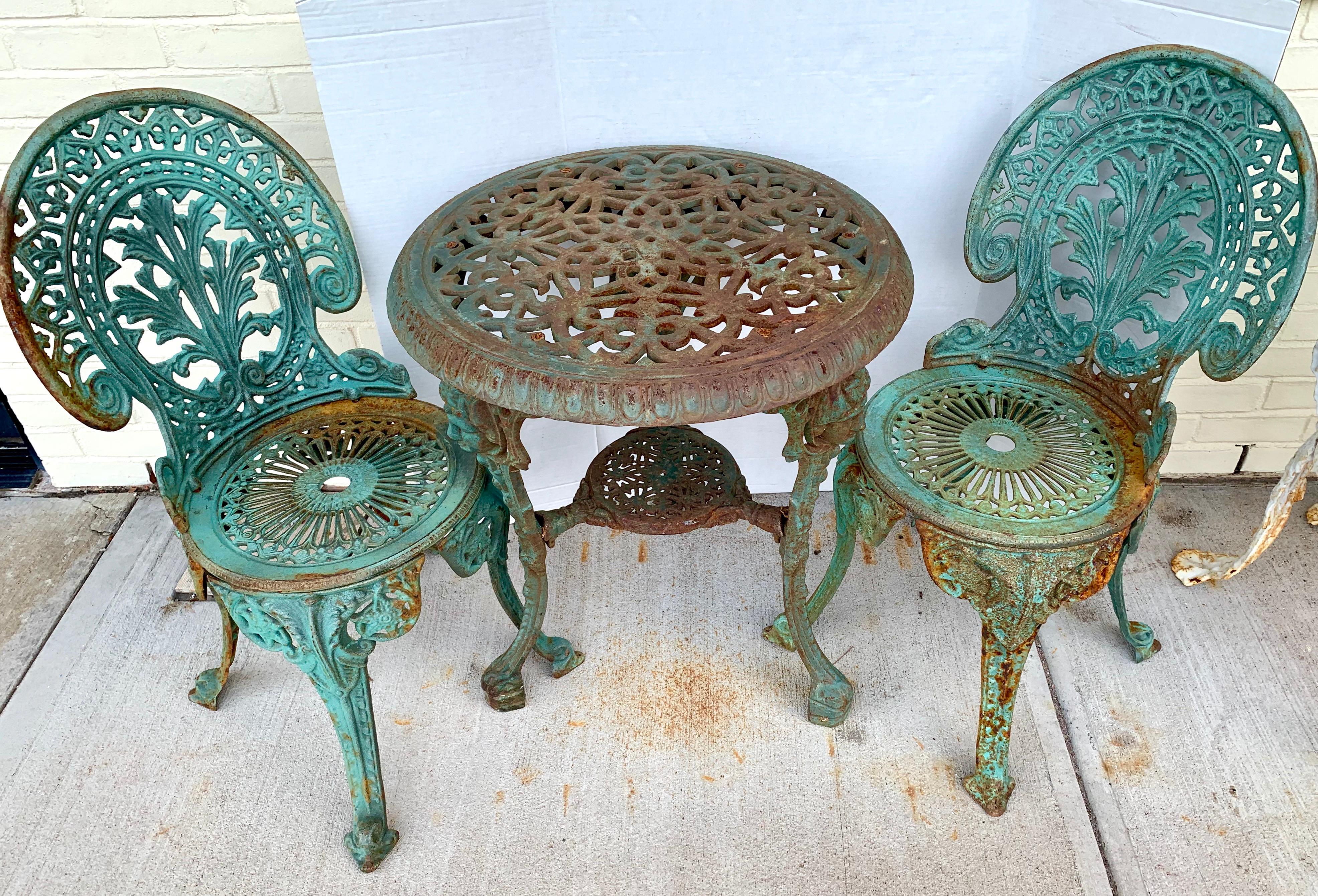 Lovely antique green cast iron outdoor bistro set that includes a round table and two chairs. The set has remarkable figural detail which is highlighted by the three carved Roman male heads that adorn the three
legs of the table. The set has quite
